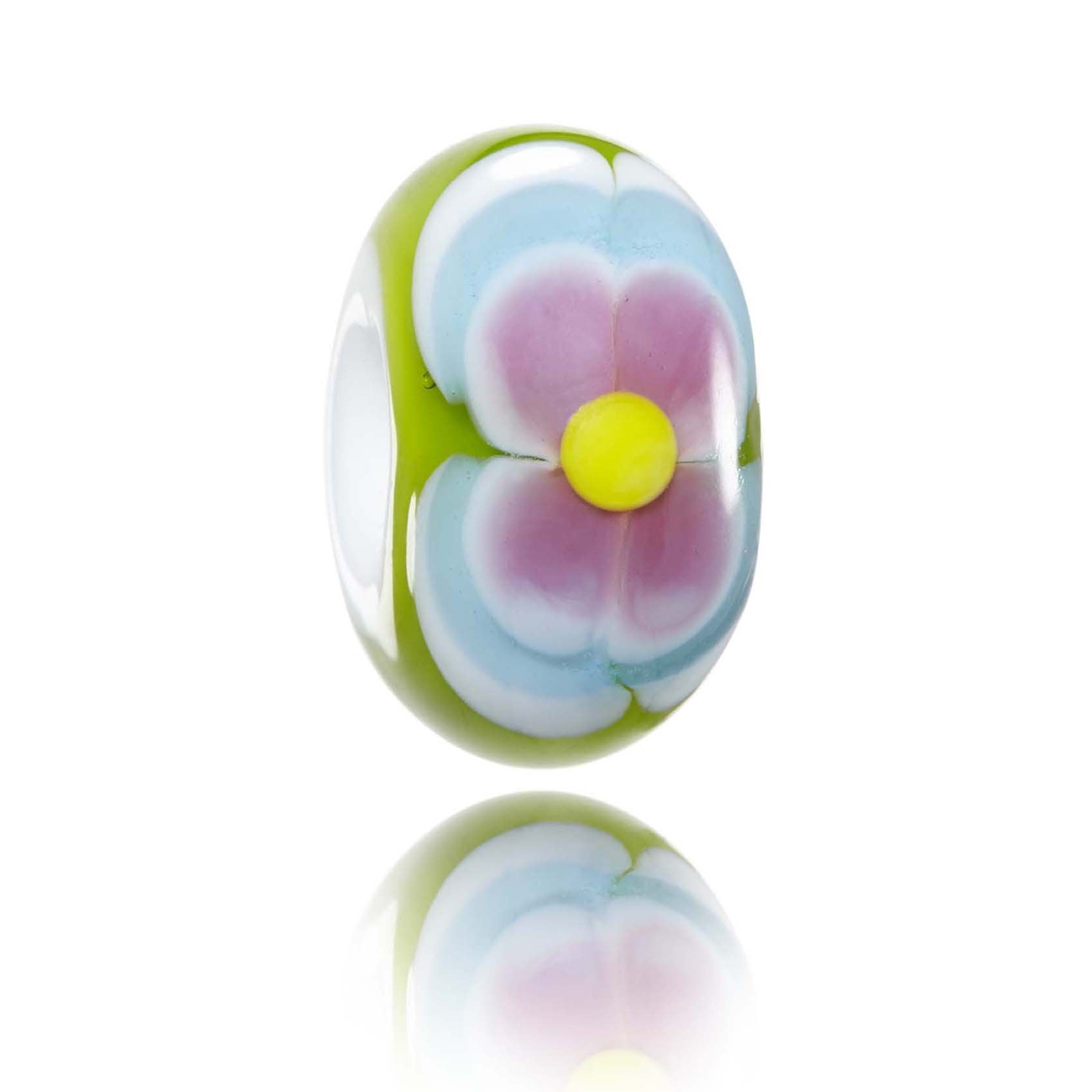 Green glass bead with a blue and pink flower pattern on the surface. Representing Oahu Island in Hawaii.