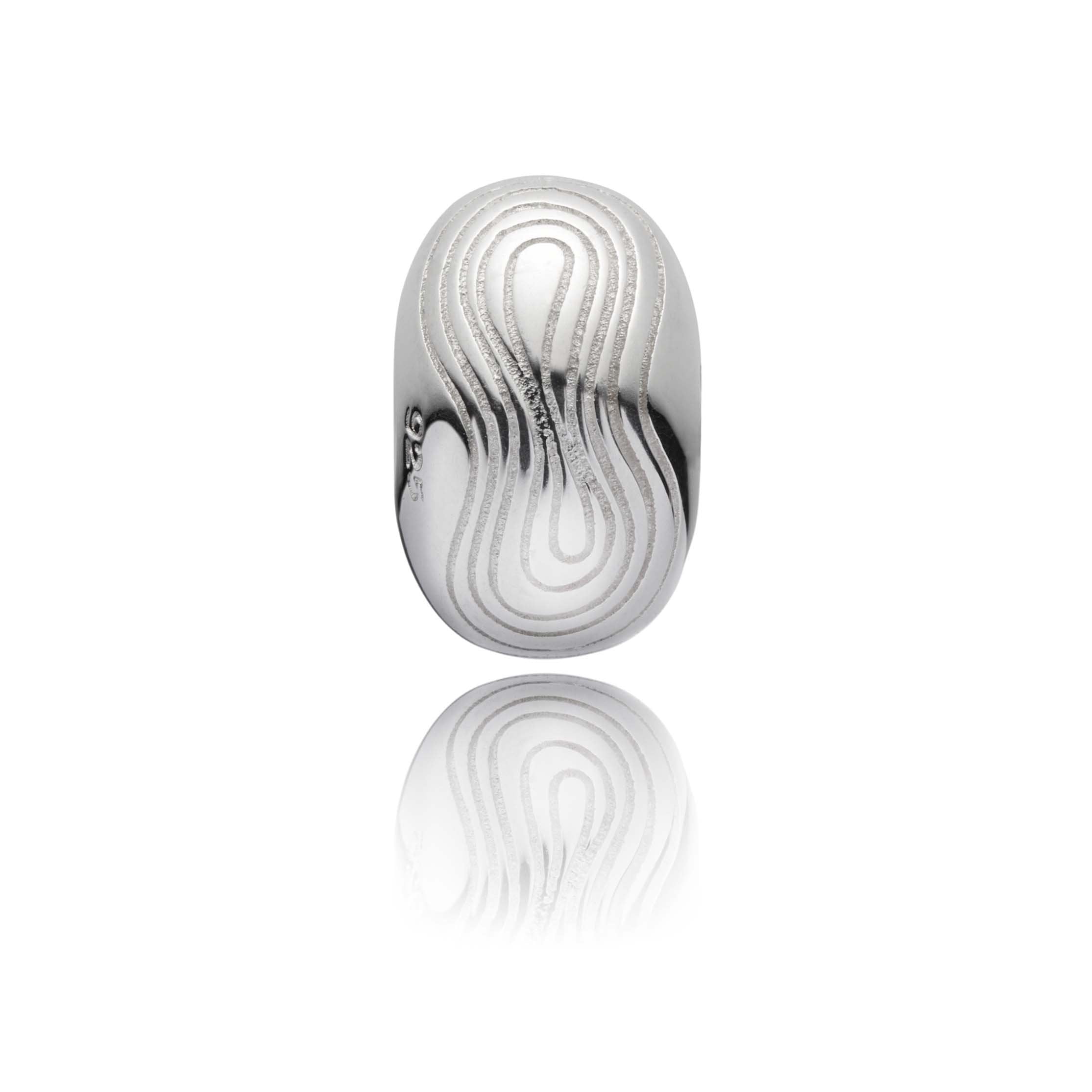 Silver swell bead with swell patterns engraved on the surface.