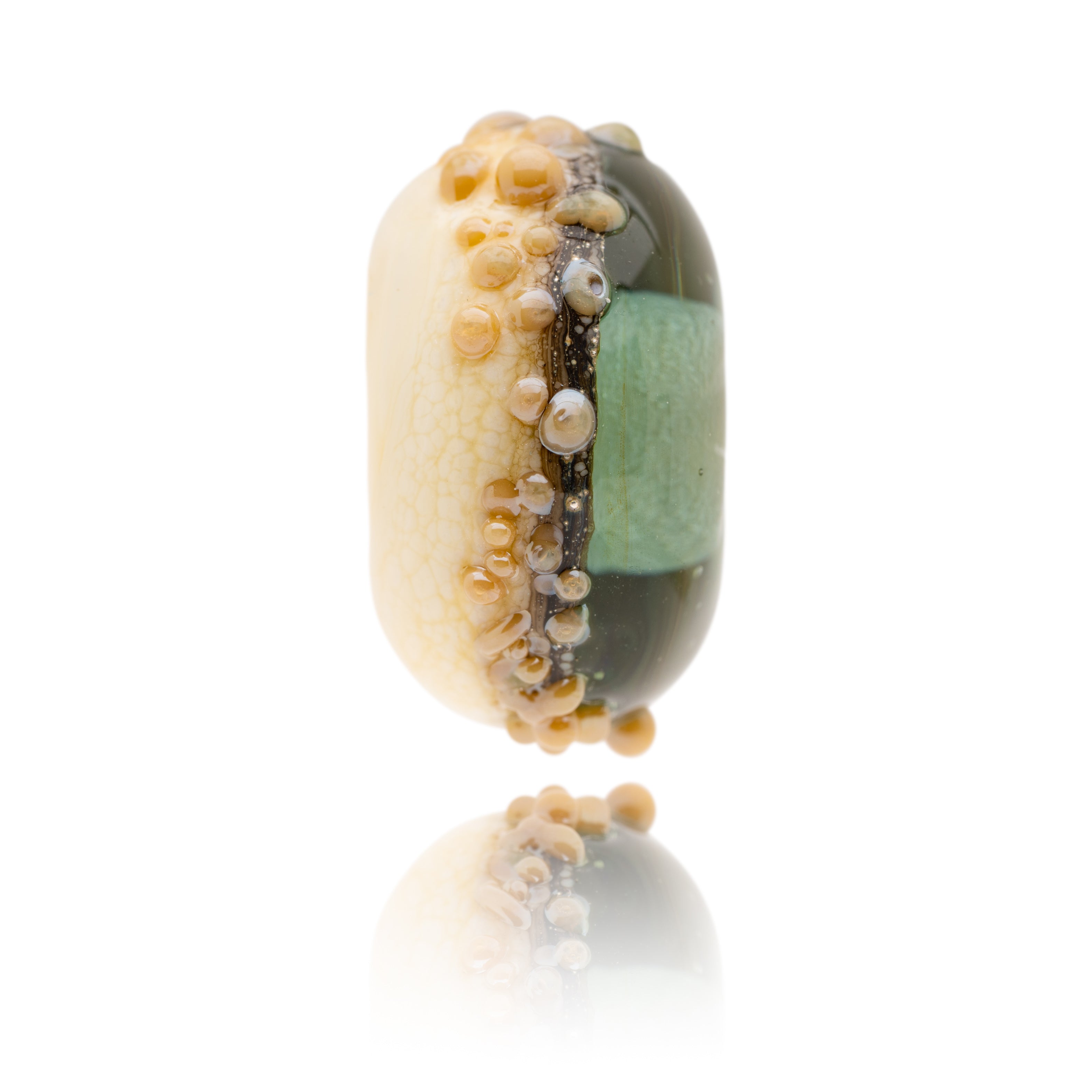 Green and ivory glass bead decorated with raised dots of brown glass, representing Worthing Beach in Sussex.