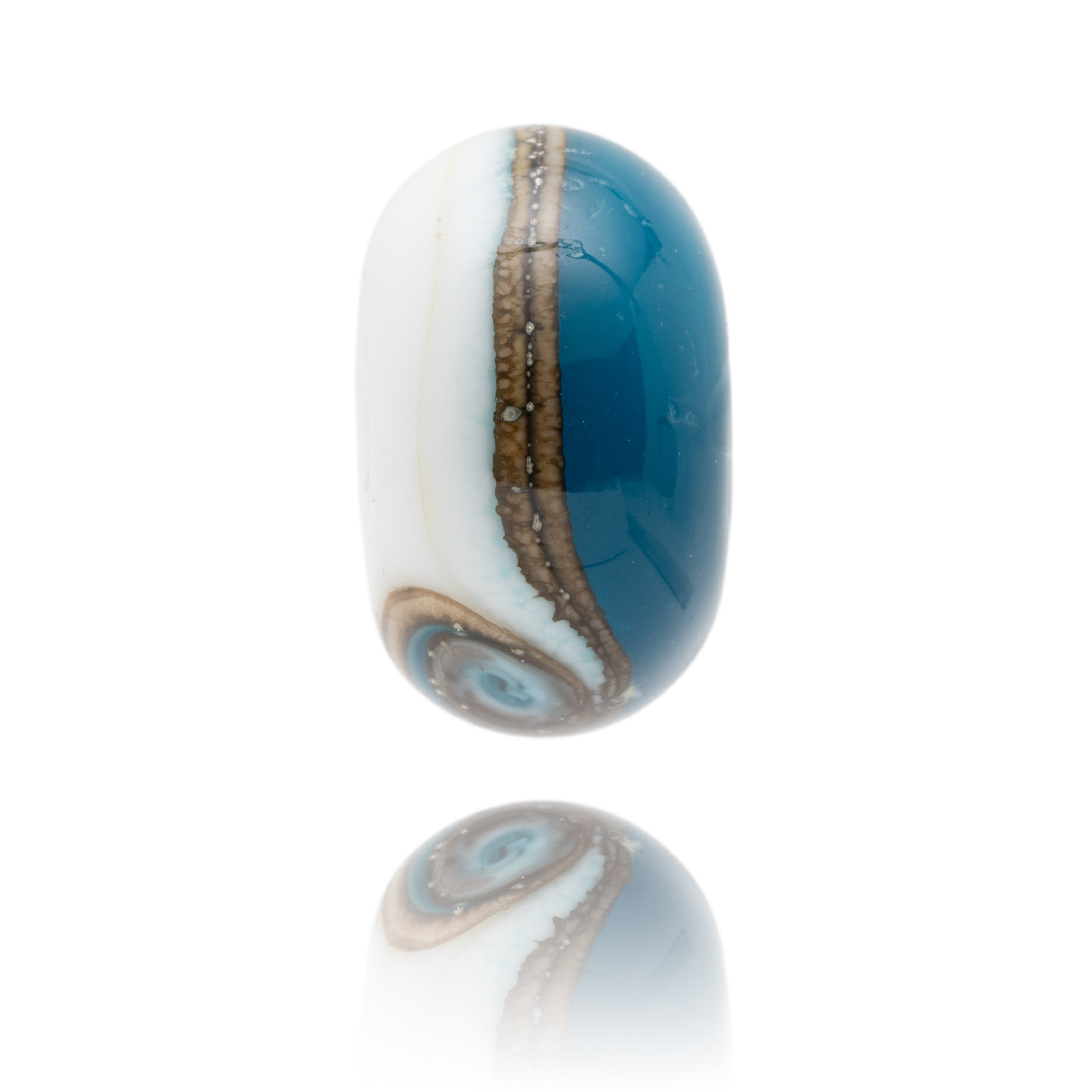 White and dark blue glass bead with silver swirl around middle representing a beach break.