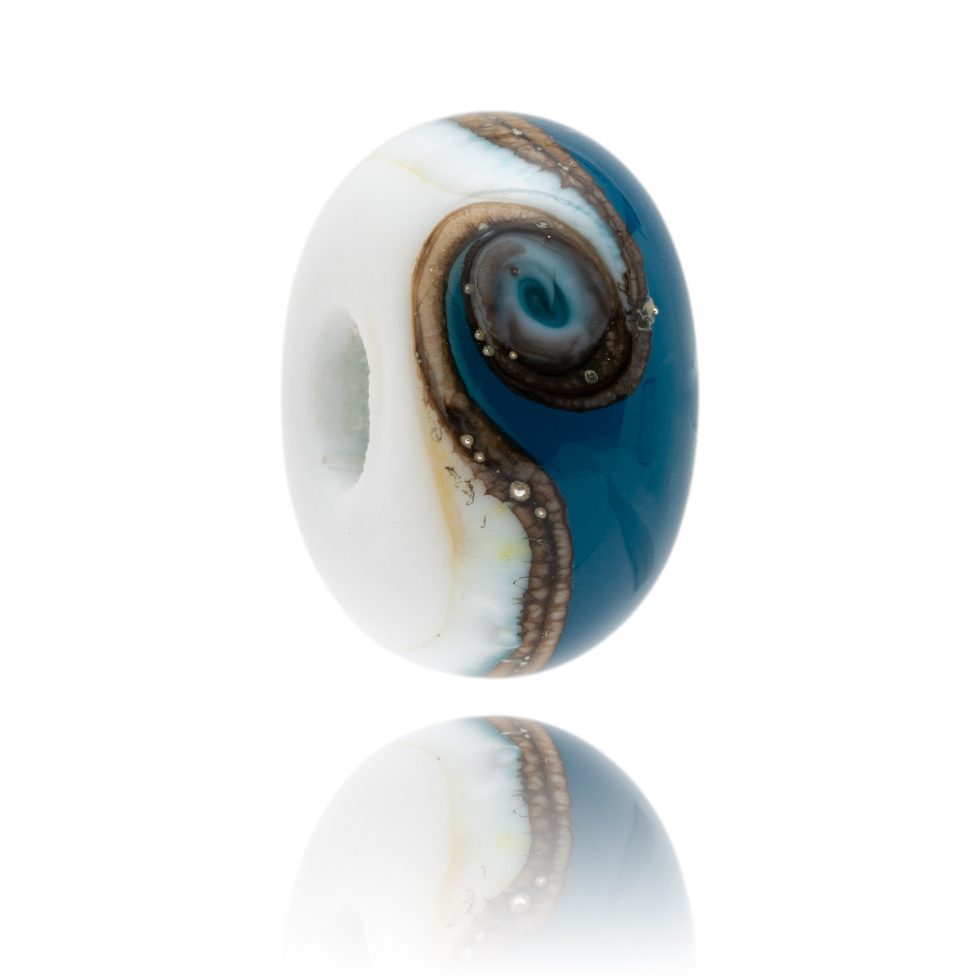 White and dark blue glass bead with silver swirl around middle representing a beach break.
