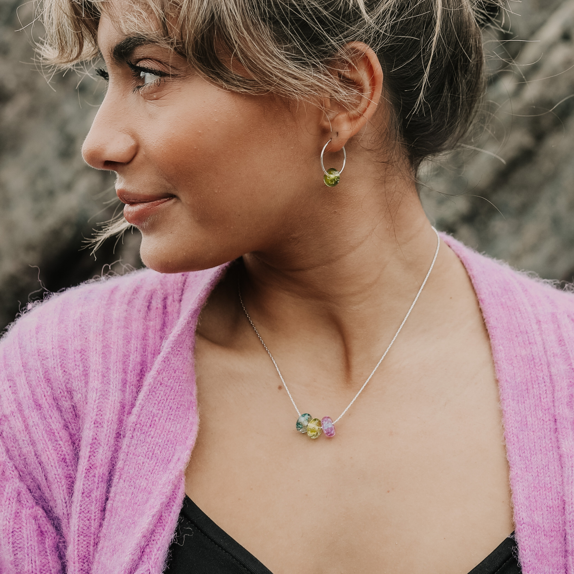 Lady wearing silver chain necklace with grey, green and pink glass sand beads,