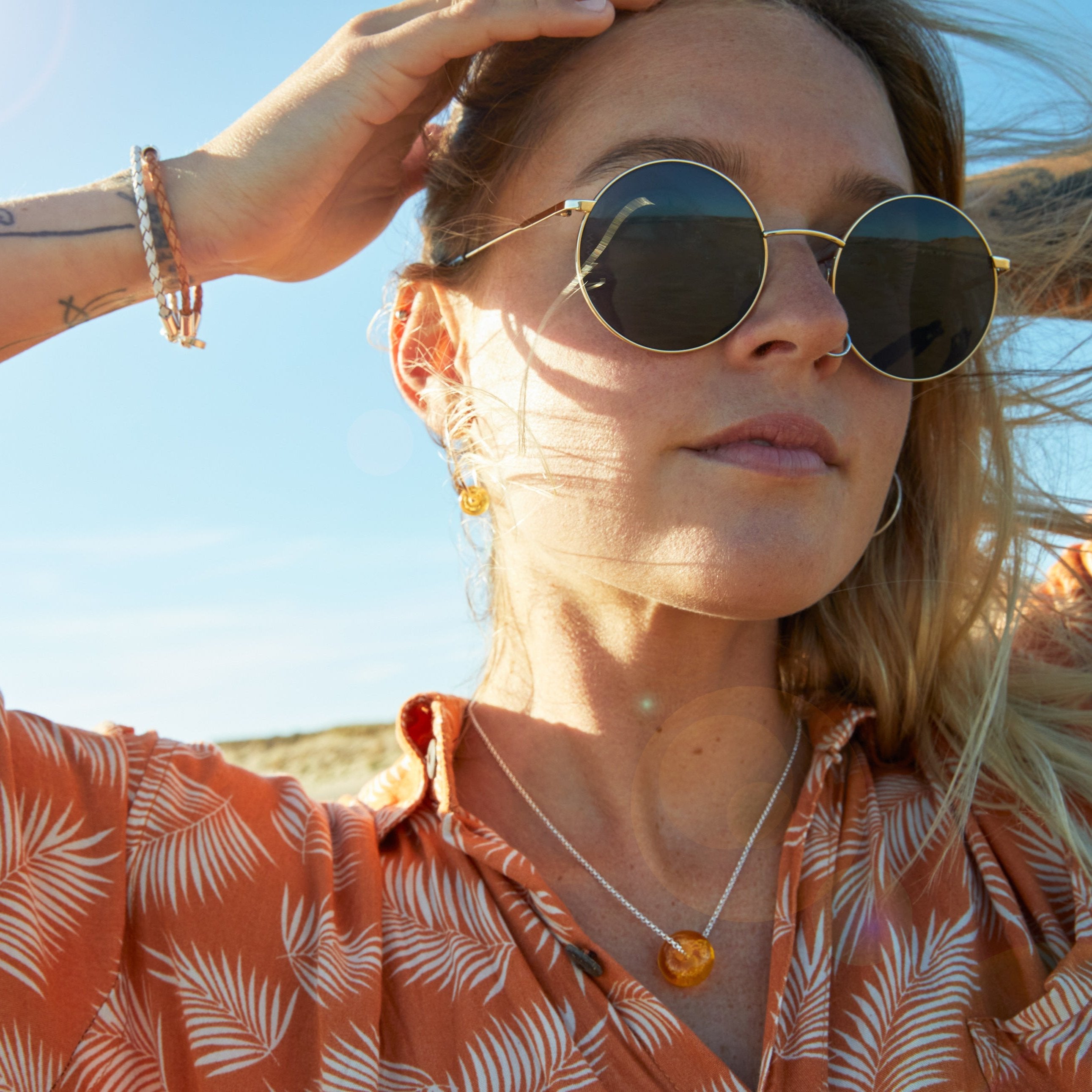 Girl wearing sand beads on beach in Dorset.