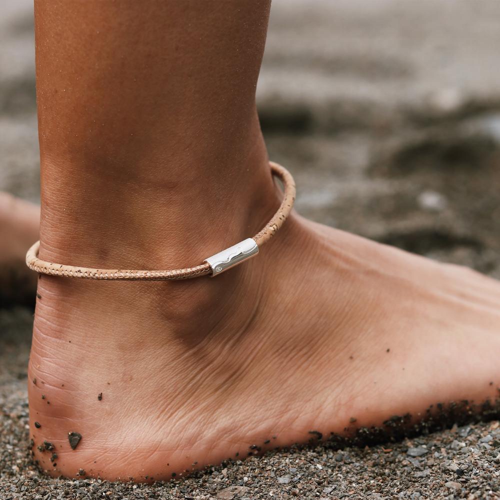 Person wearing cork anklet with silver tube charm.
