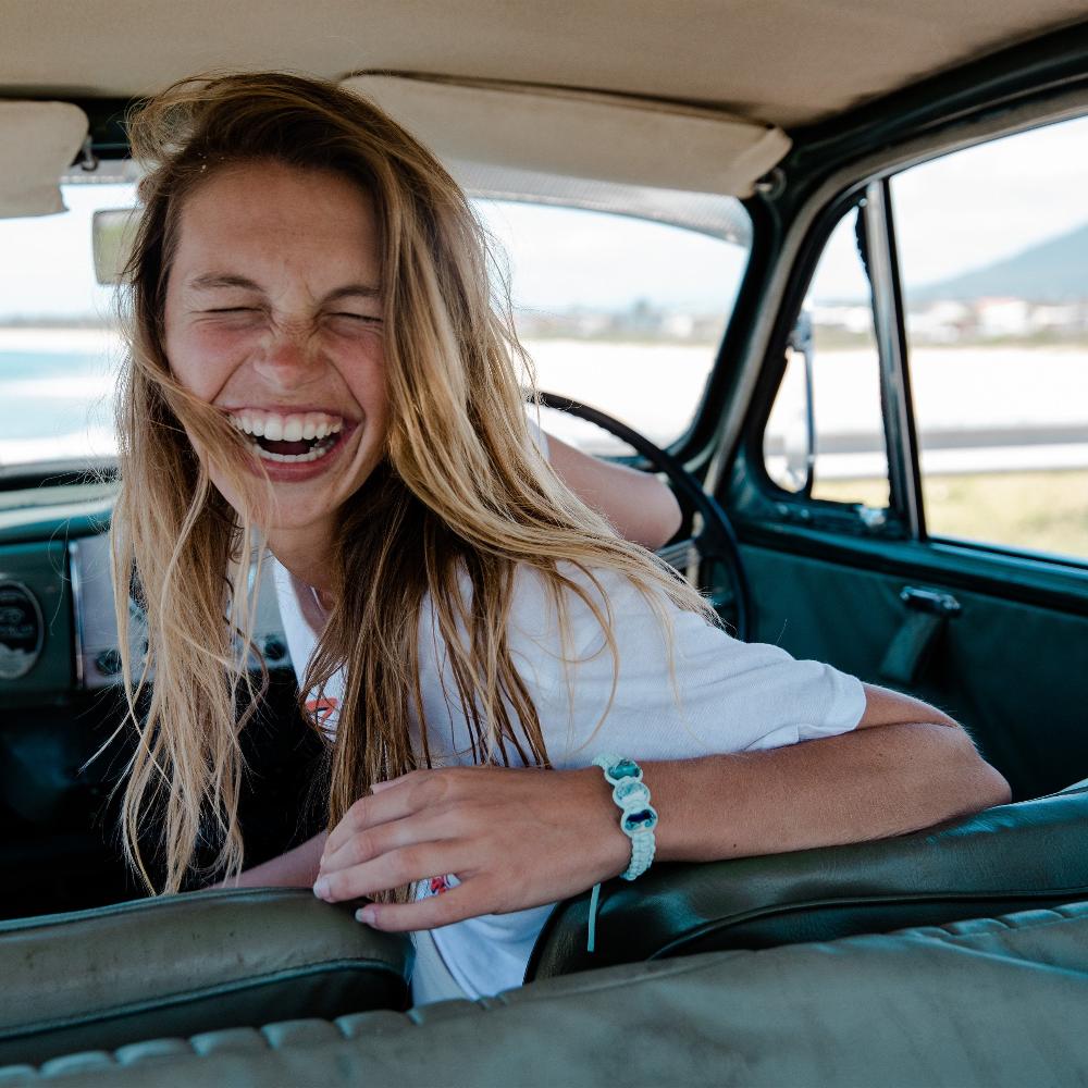 Girl in car laughing wearing mint bracelet with beads.