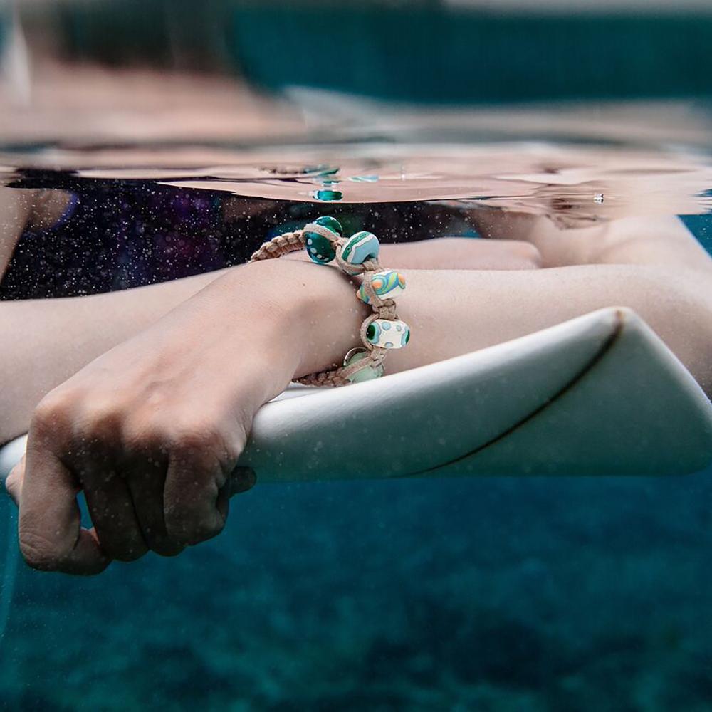 Surfer in the sea wearing a cord beaded bracelet.
