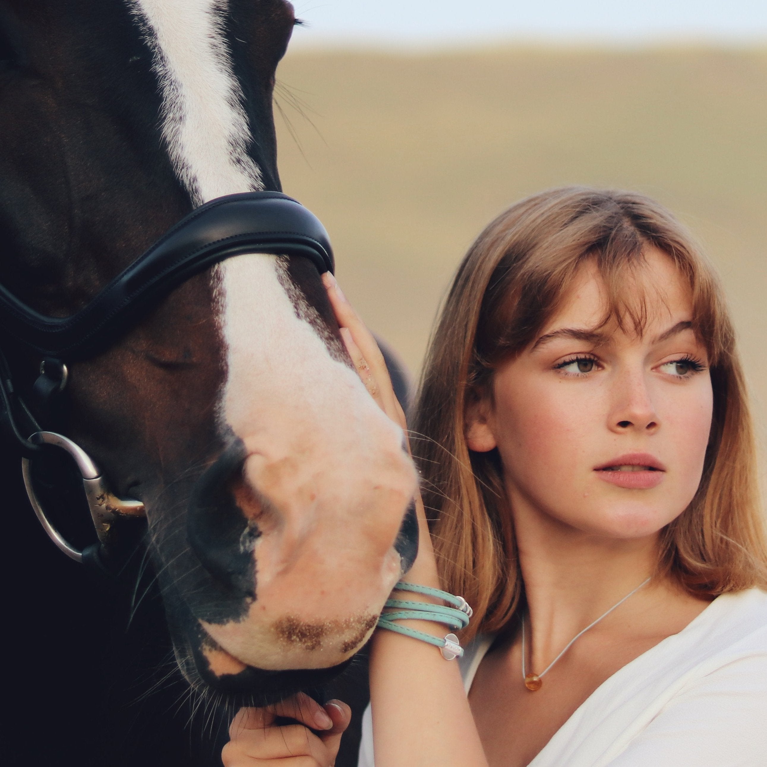 Girl with horse on the beach wearing turquoise cork bracelet.