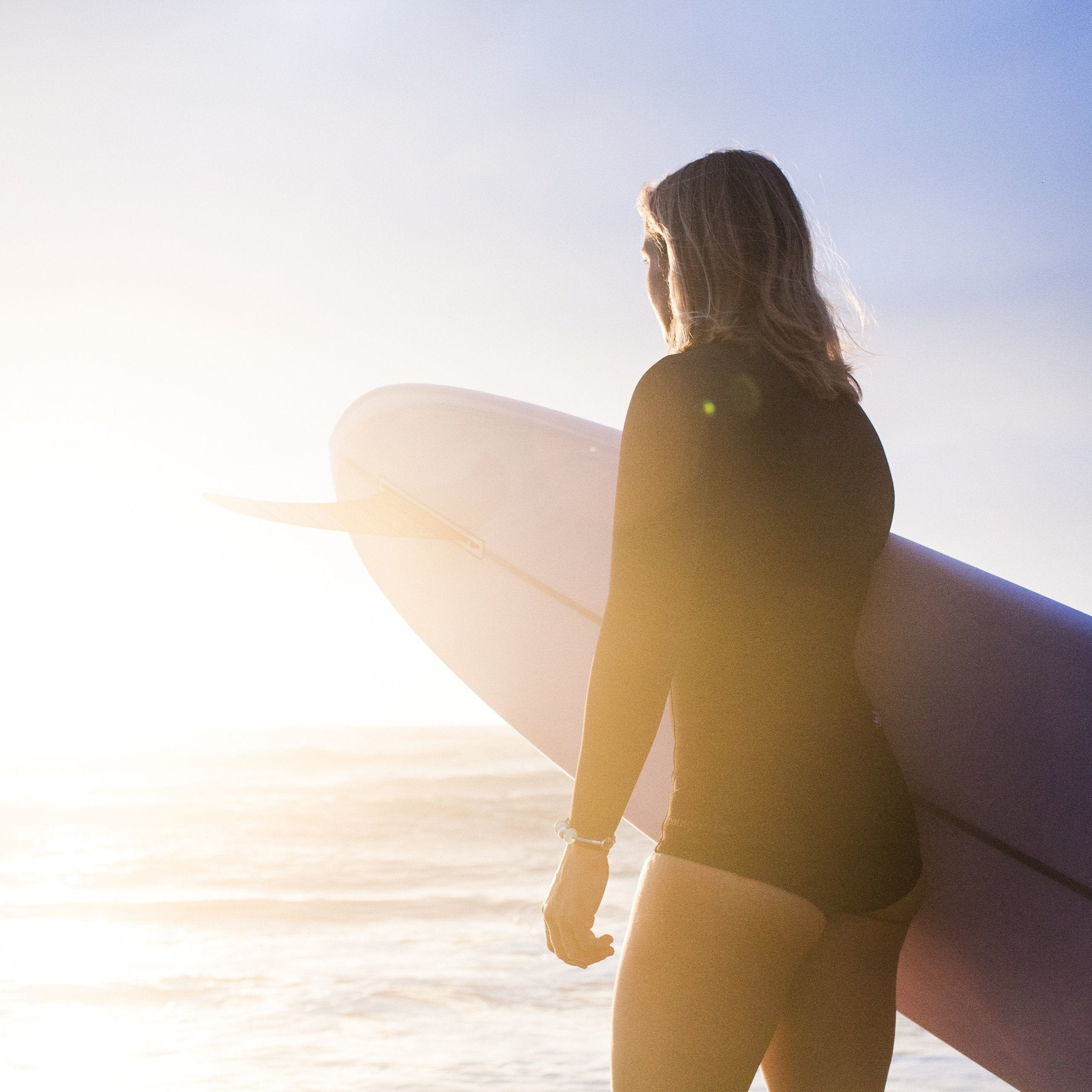 Surfer woman holding surfboard at the beach.