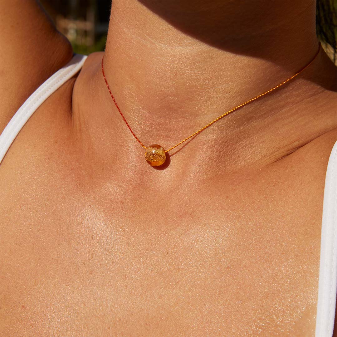 Woman wearing a amber glass pebble necklace.