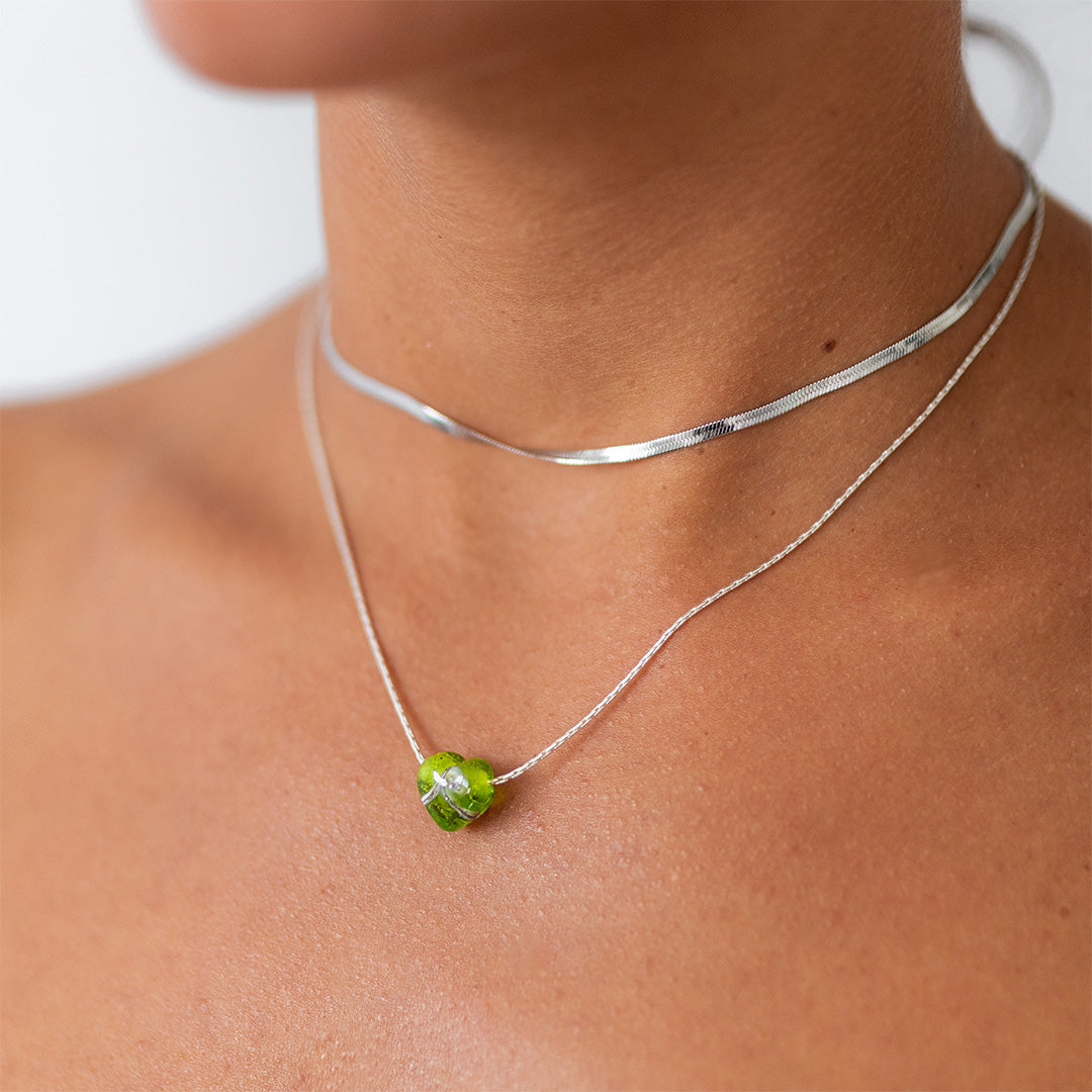 Tropical Green sand heart necklace on a silver chain worn by a woman.