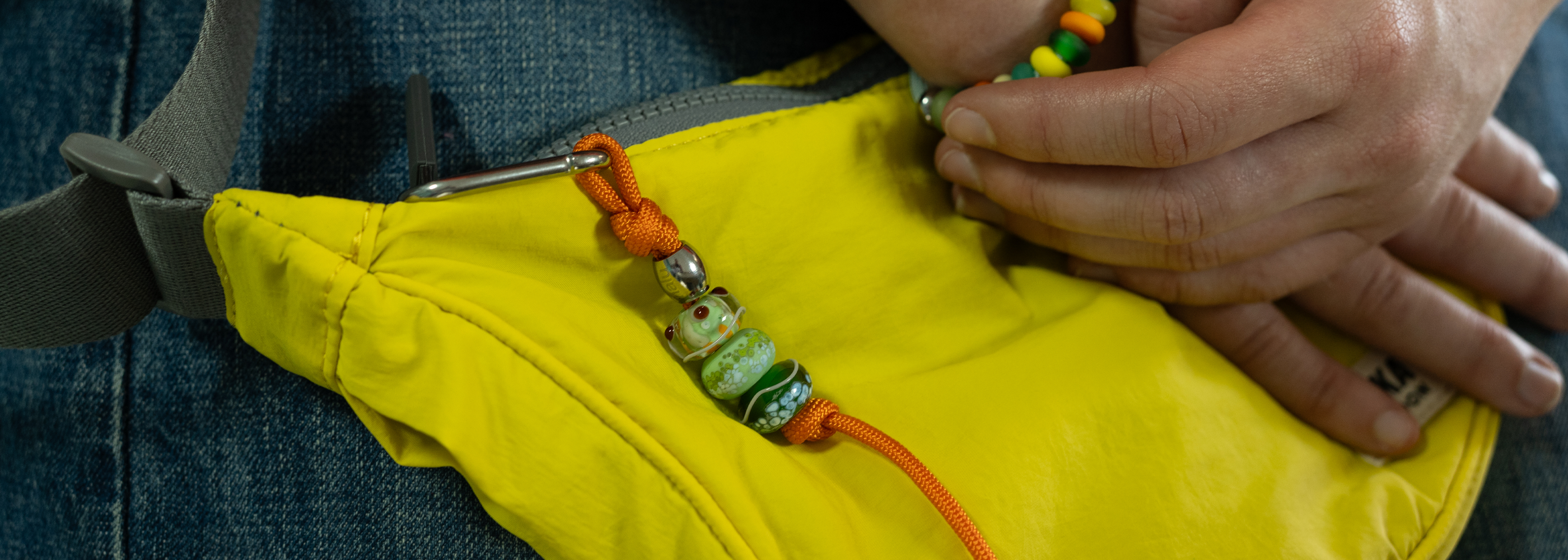 Person adjusting a yellow bag with colorful straps.