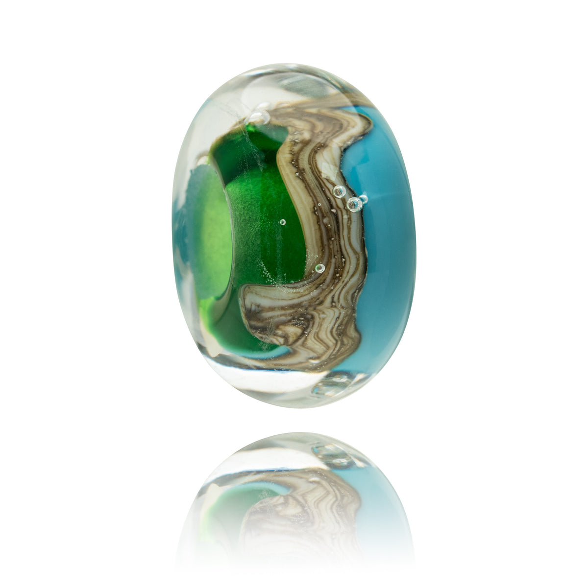 An oval glass lampwork bead with a swirling pattern of turquoise blue, vibrant green, and brown, resting on a reflective white surface.
