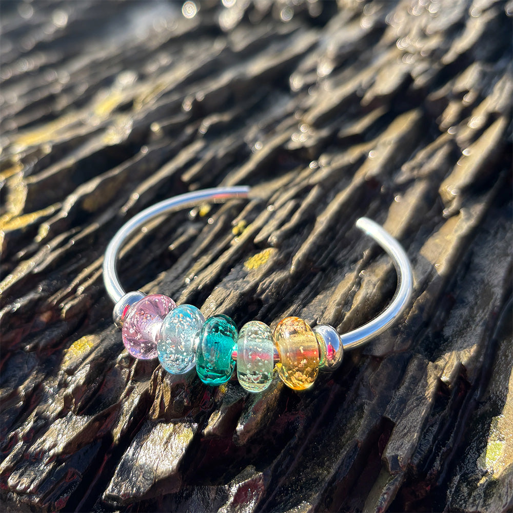 Colourful glass beads on a silver bangle on the reef.