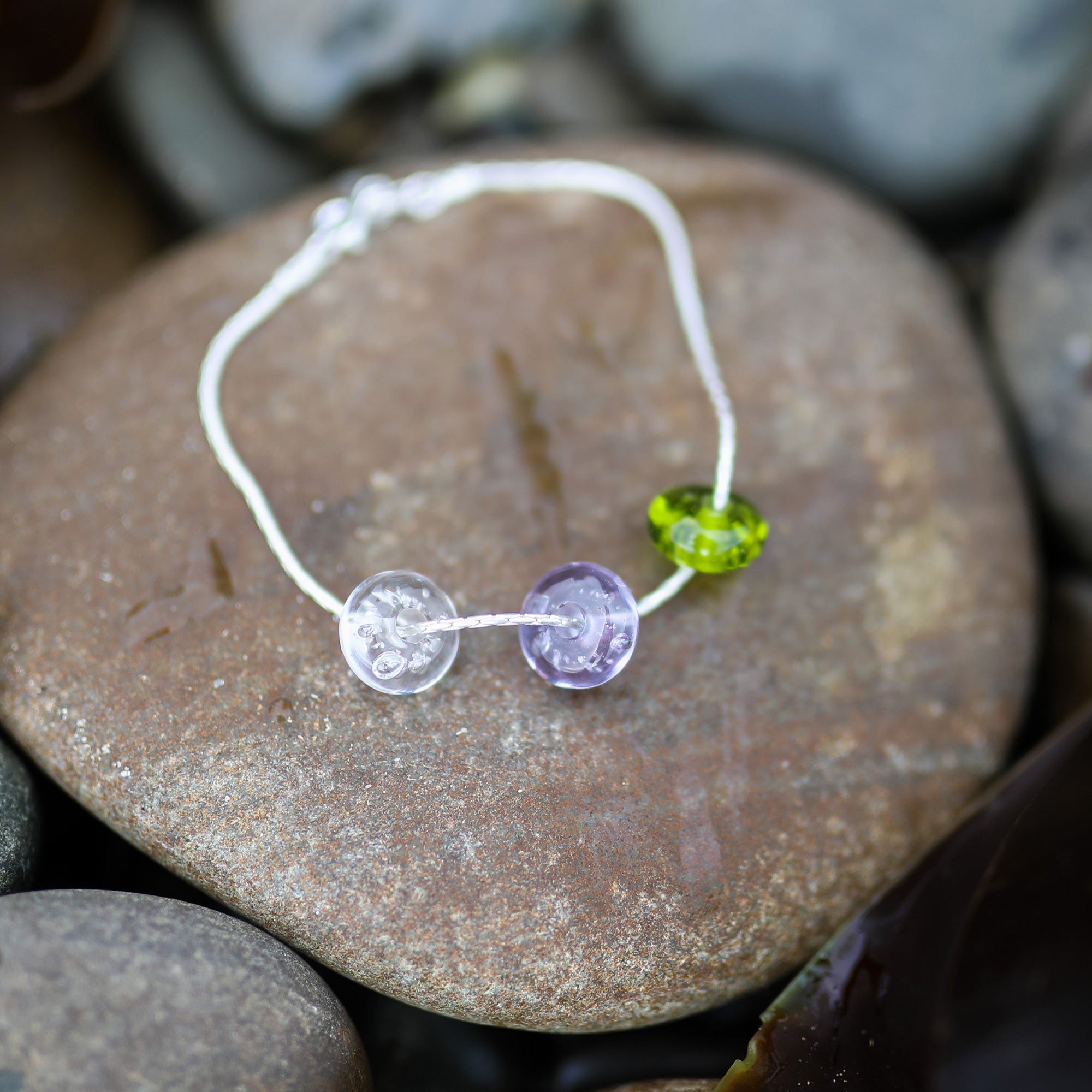 Sterling silver fine chain bracelet with clear, lavender and apple green beach sand beads,on pebble on Croyde Bay. Handmade to order in North Devon.