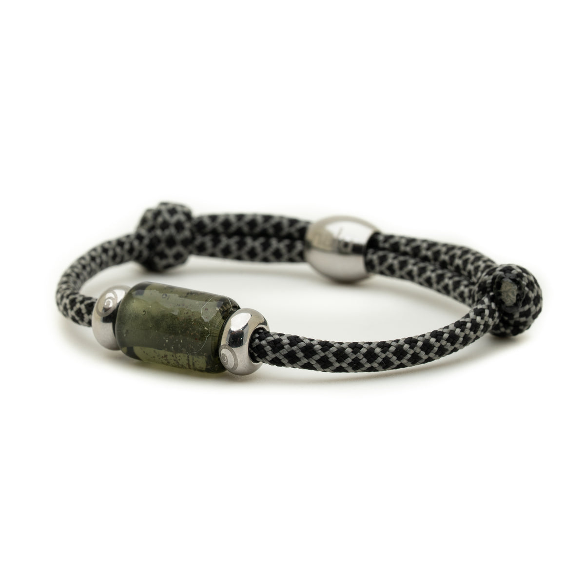 A black and white woven cord bracelet with a central green stone bead and silver metal spacers, shown on a plain white background.