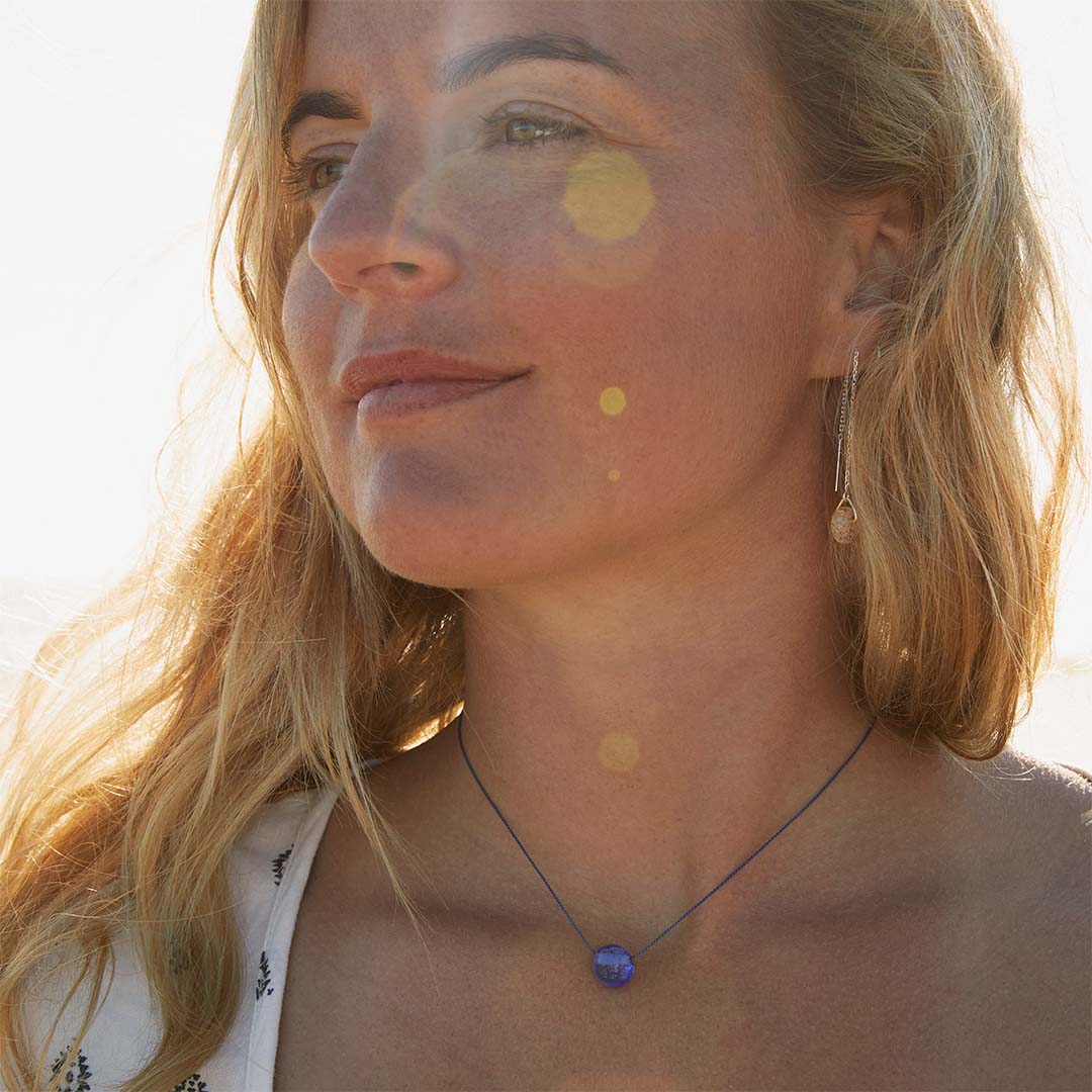 Woman wearing a silk pebble necklace and hoop earrings.