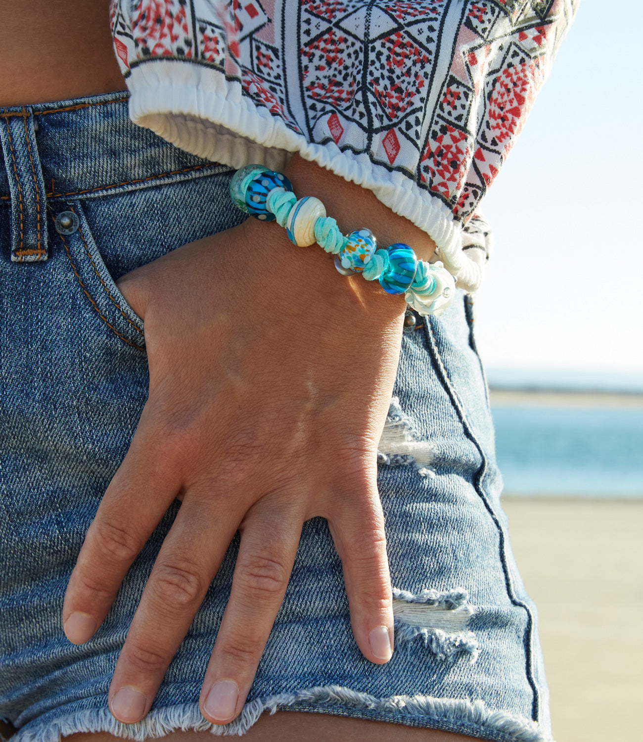 Mint colour vegan cord blue beaded bracelet worn by girl in denim shorts on Saunton Beach.