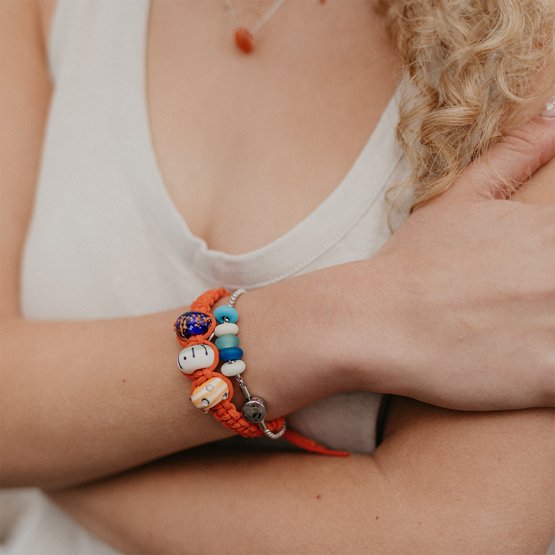 Girl wearing coral bracelet with bright blue, yellow and green glass beads.