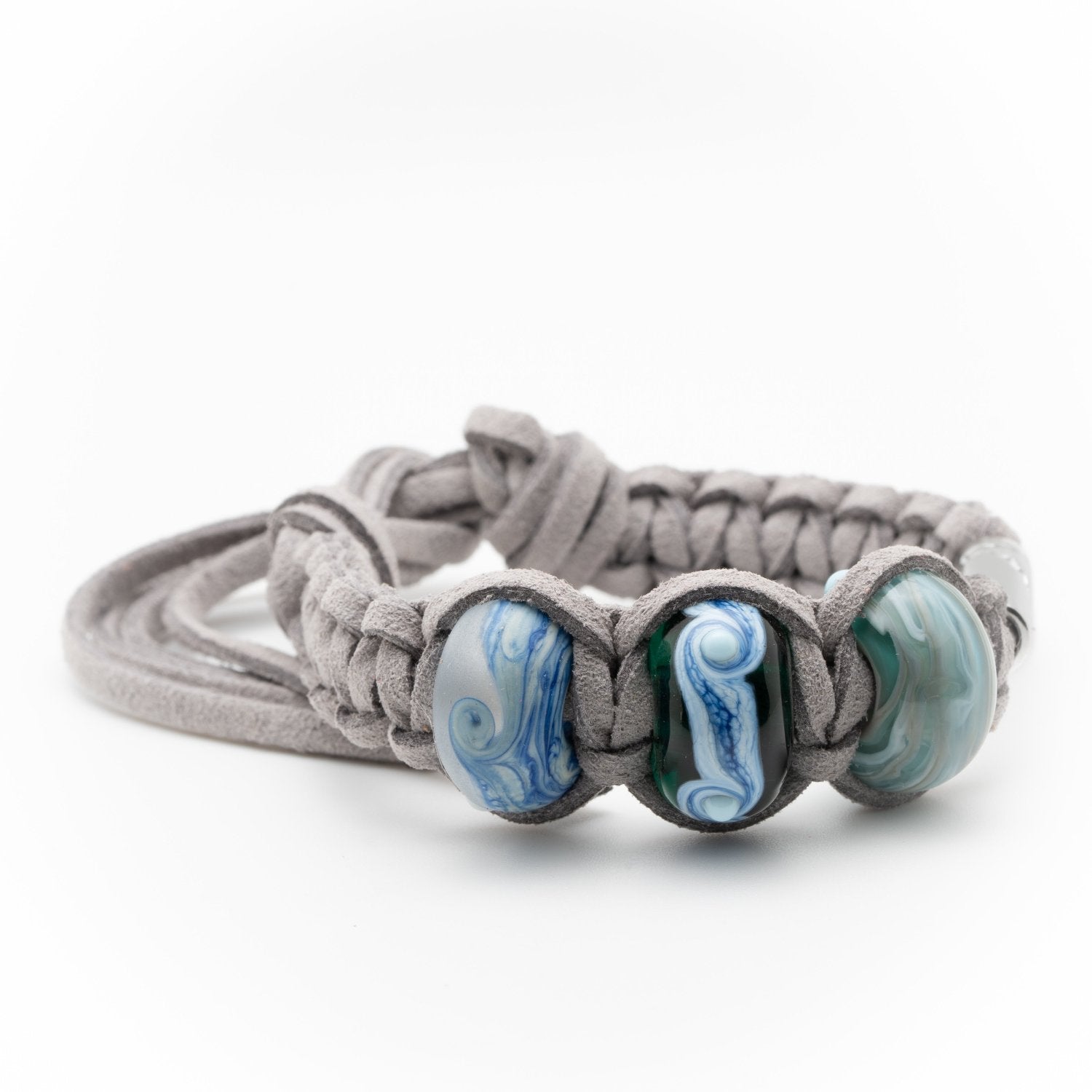 Grey cord bracelet with three blue glass patterned bead woven into it.