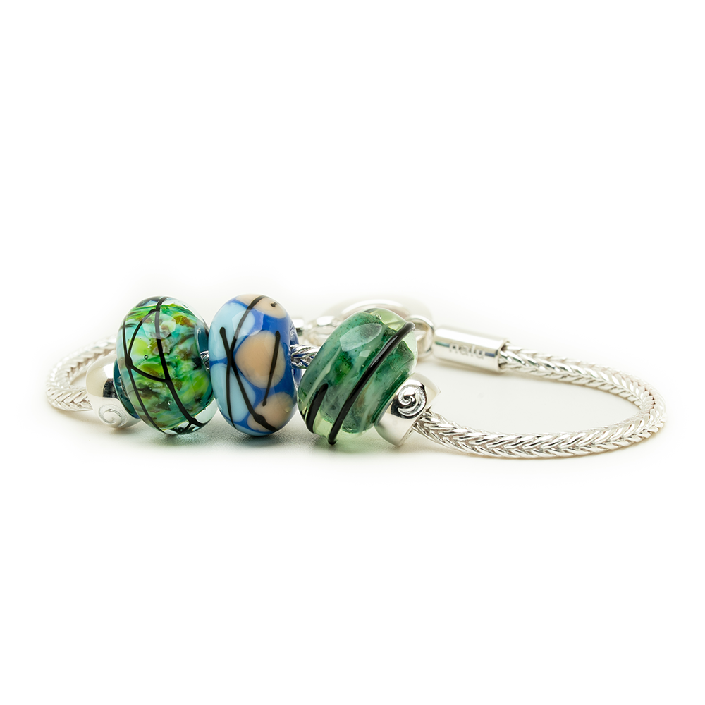Three colorful glass beads on a silver bracelet against a white background
