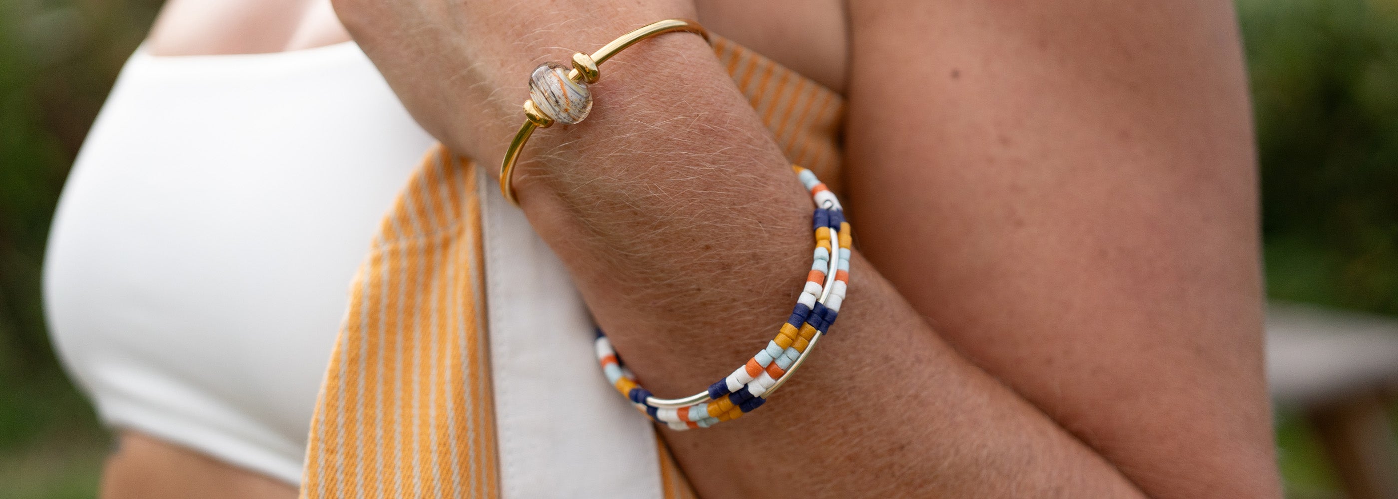 Close-up of a person's arm wearing two beaded bracelets with a blurred background