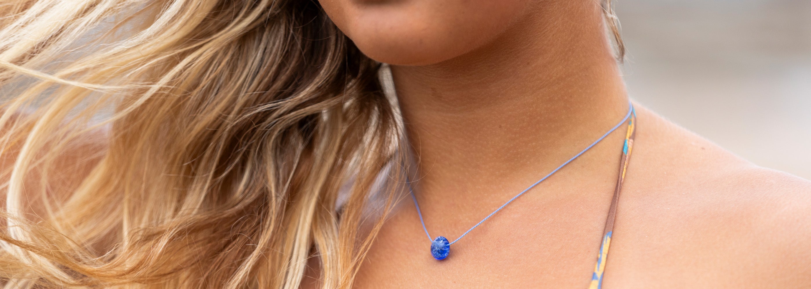 Dark blue glass sand pebble on blue silk necklace.