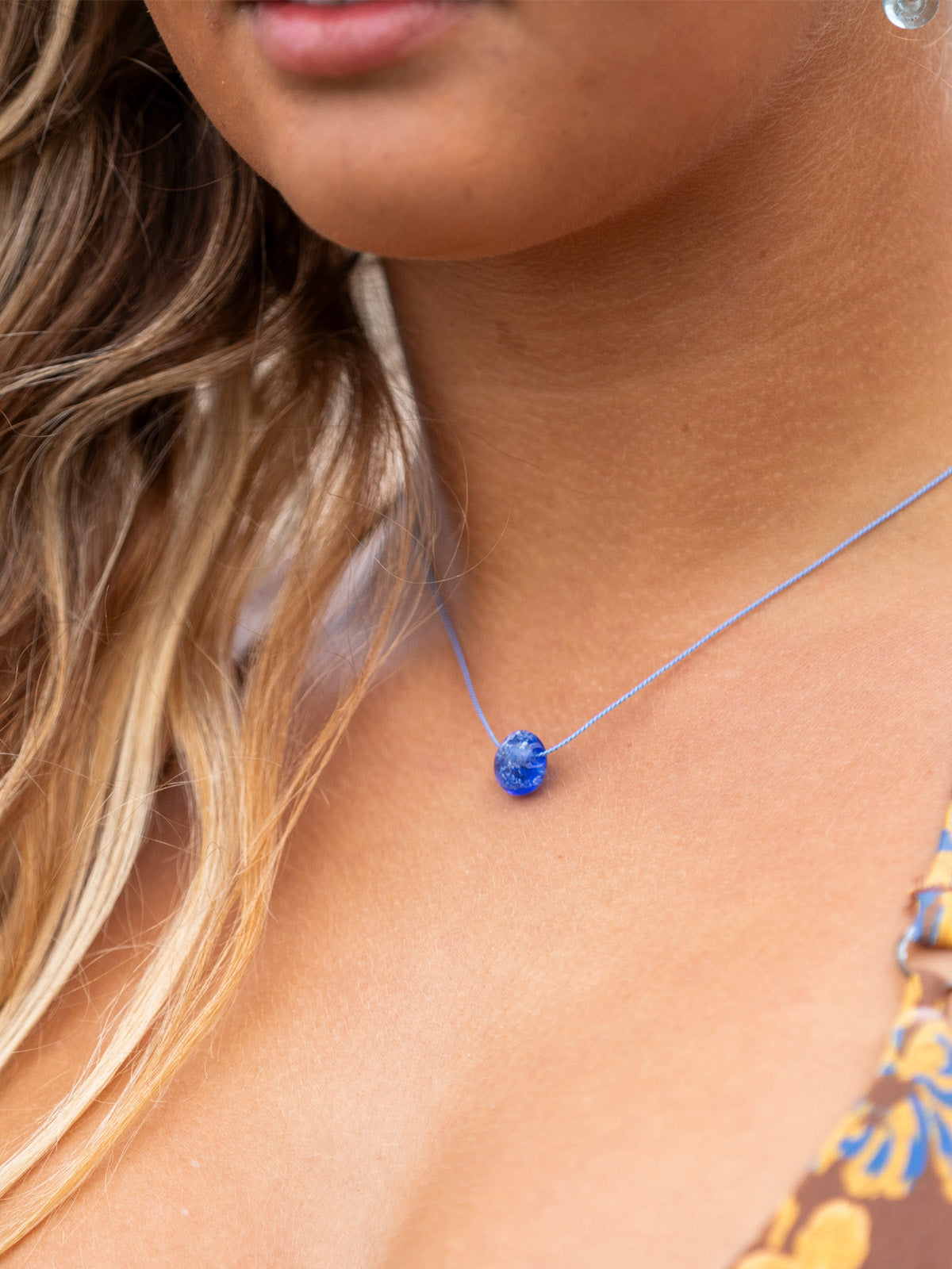 Dark blue glass sand pebble on blue silk necklace.