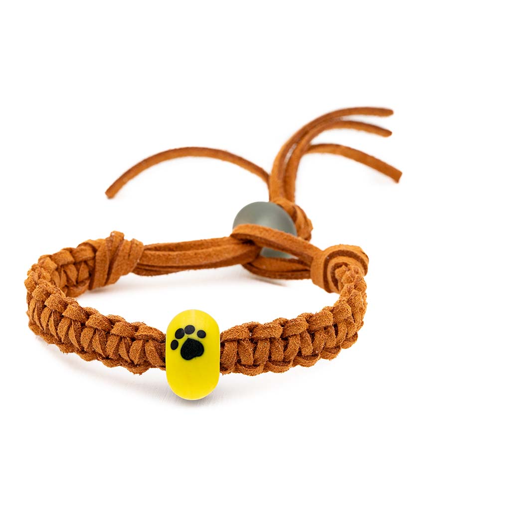 Bright yellow glass bead bracelet with a black paw print, being sold to support the Dogs Trust.