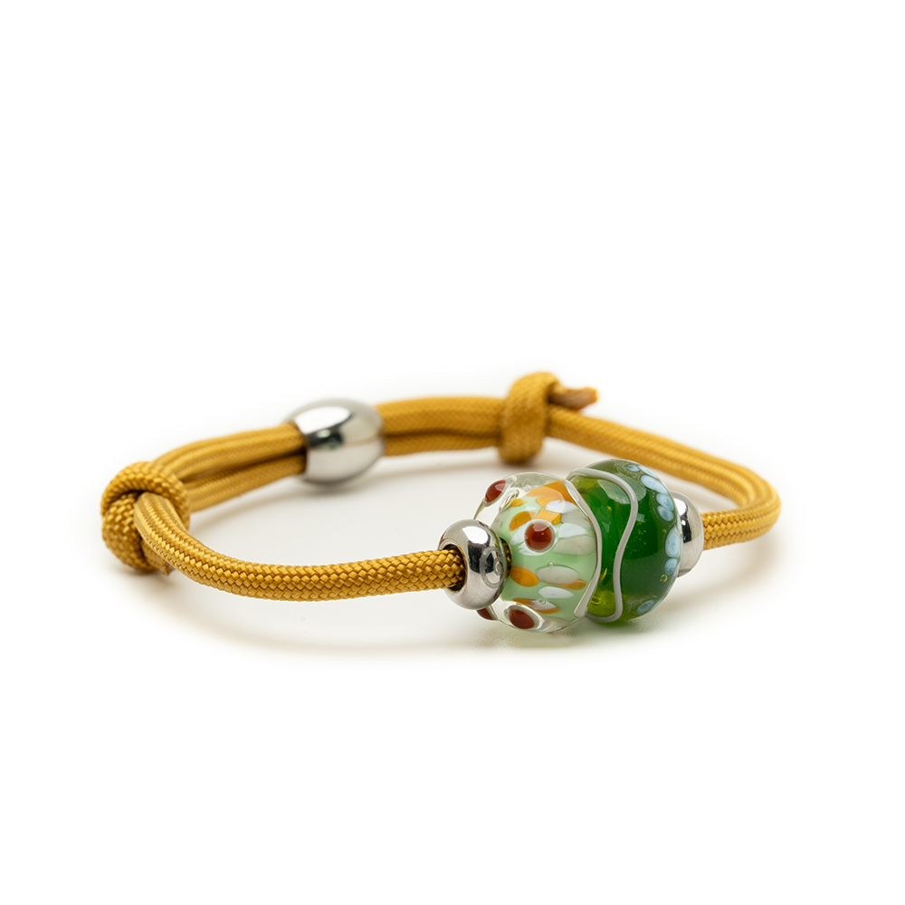 Yellow bracelet with a green and silver bead on a white background
