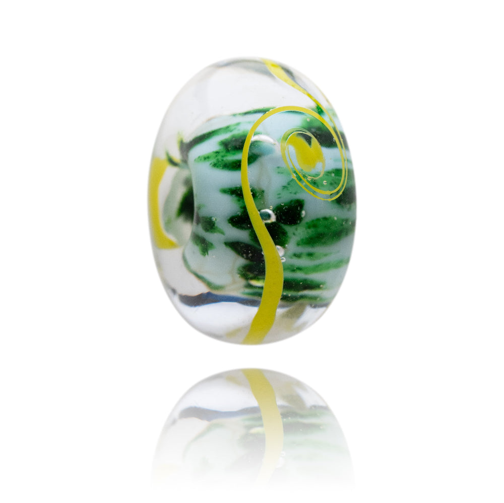 Decorative glass bead with green and yellow swirls on a white background