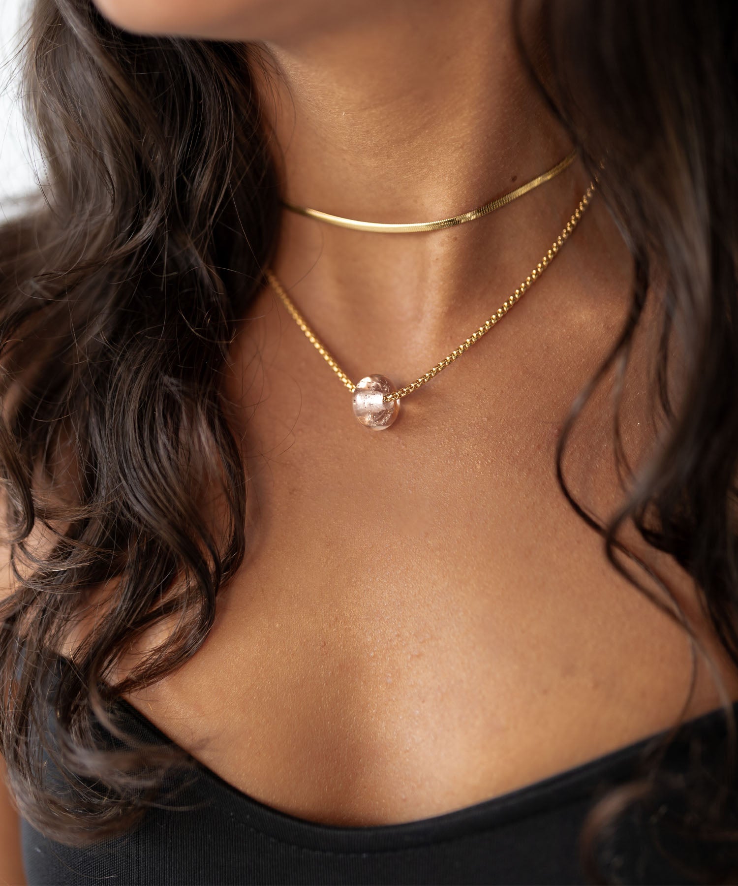 Dark haired woman wearing gold necklaces.