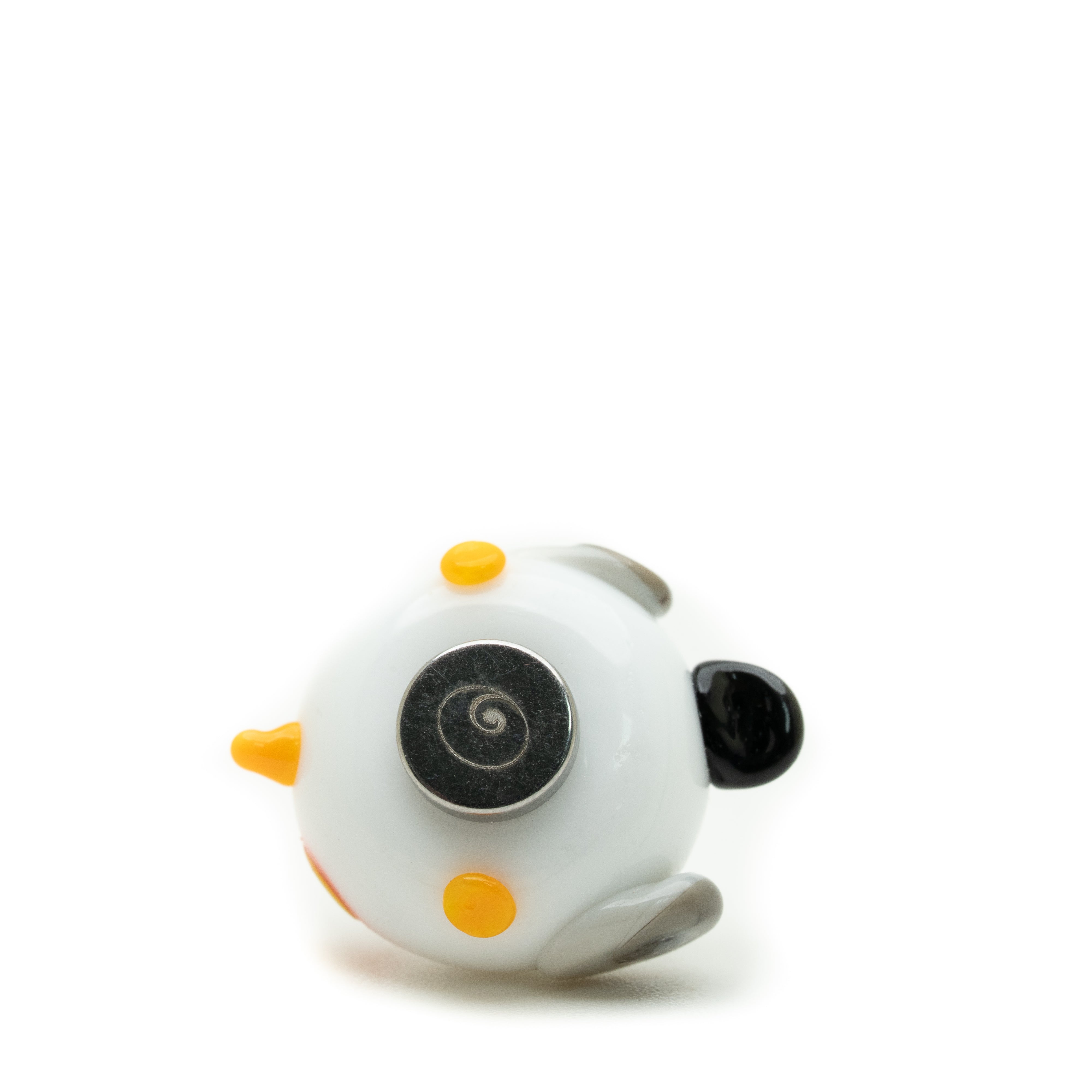 A small white seagull-shaped bead or charm with orange accents, a black ear, and a spiral-patterned eye, photographed on a plain white background.