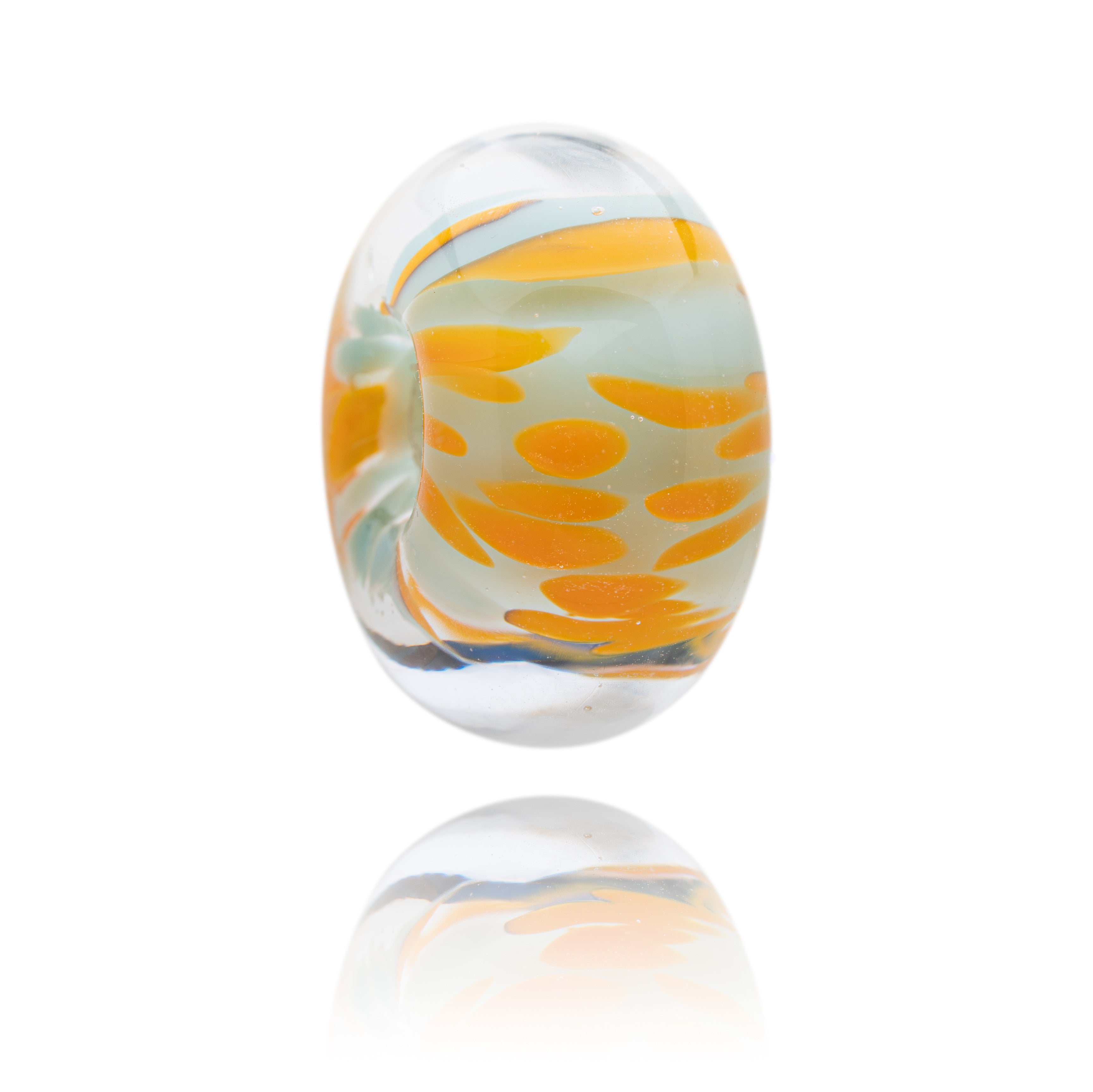 Glass bead with orange and white pattern on a white background