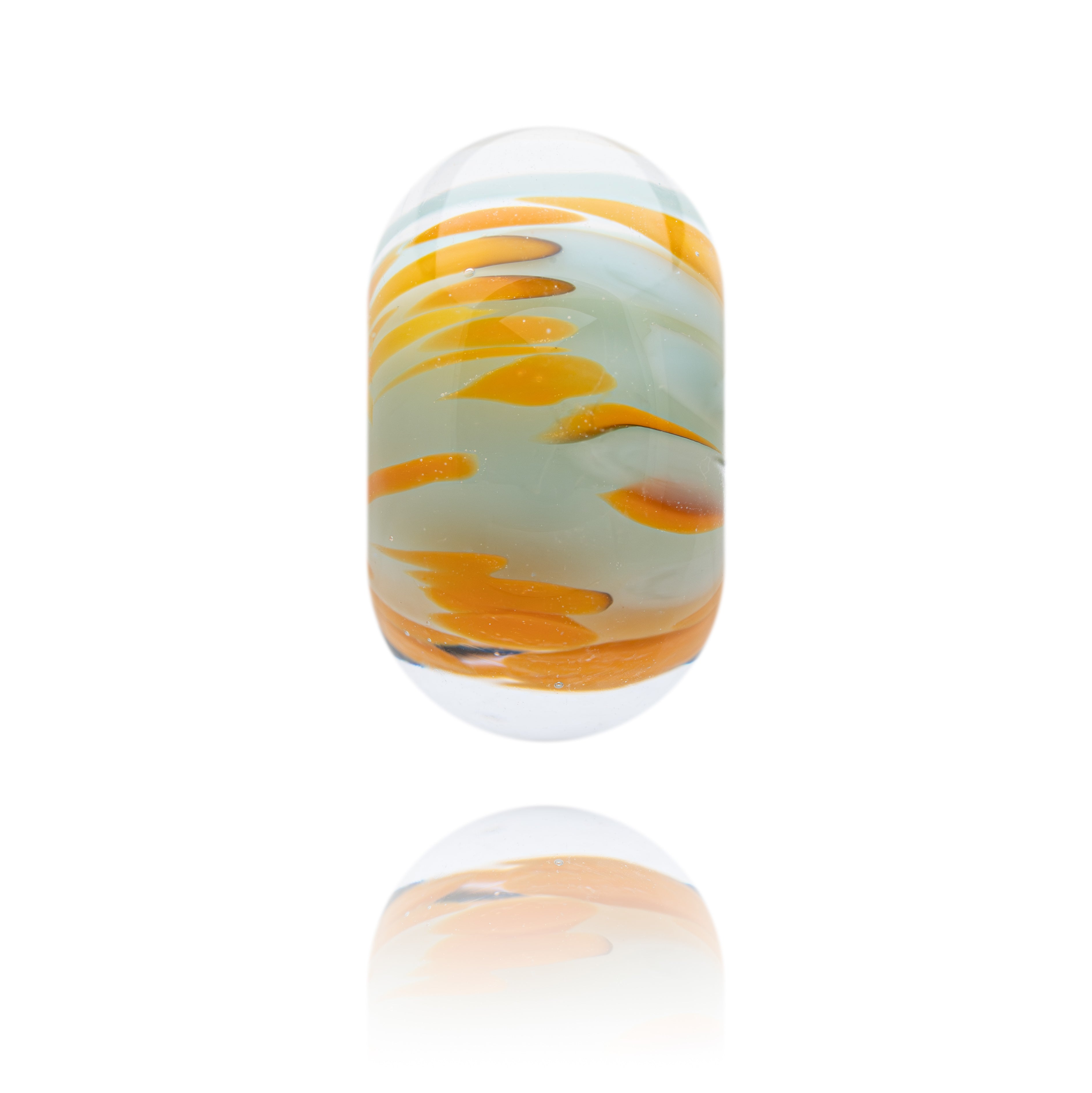 Glass bead with orange and white pattern on a white background