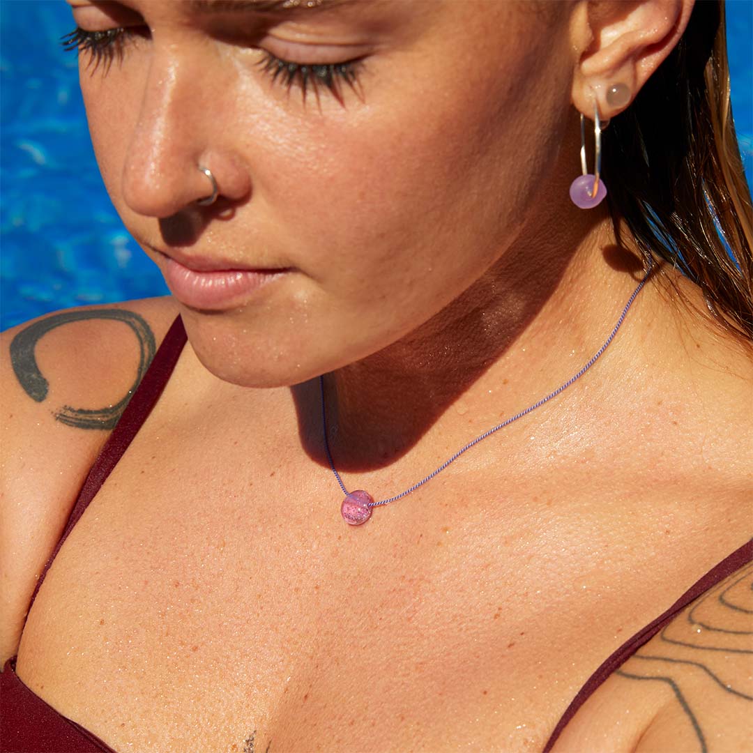 Woman in a pool wearing a Silke pebble necklace and hoop earrings.