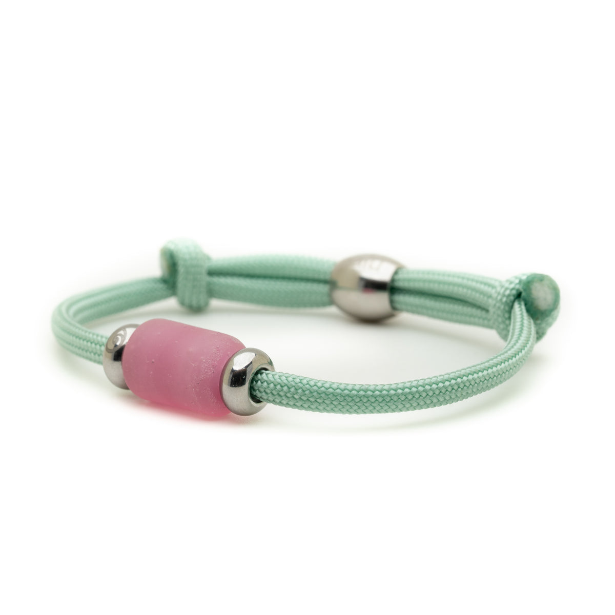 A mint green adjustable cord bracelet with a central frosted pink glass bead and silver metal spacer beads, shown on a clean white background.