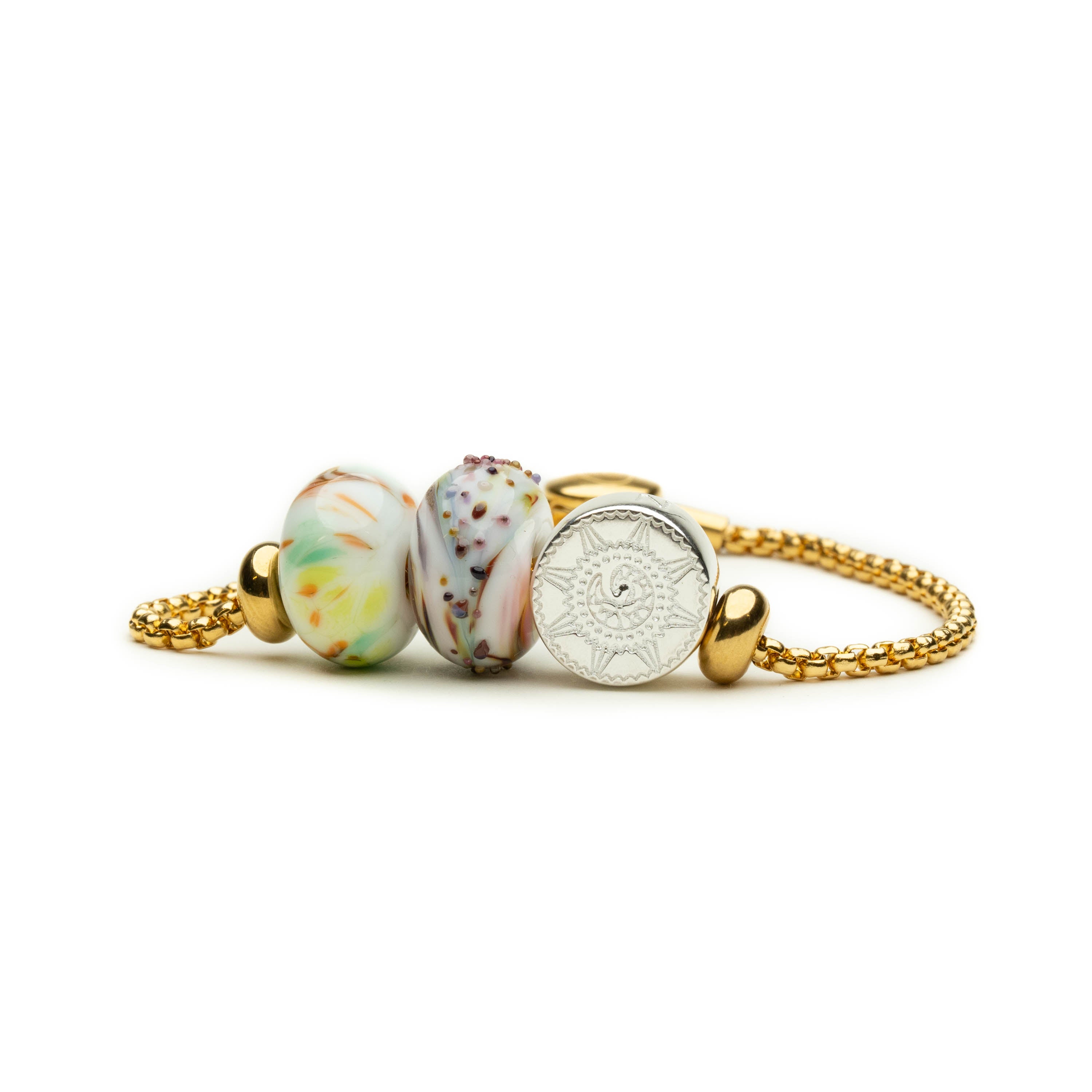 Gold ula bracelet with swirling glass beads and silver compass charm.