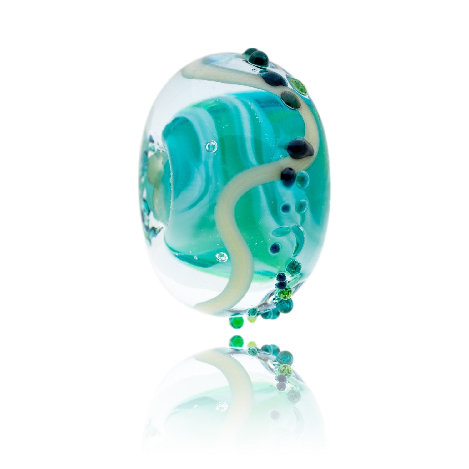 A glass bead with a swirling green core, with clear outside and specks of green and blue on the surface. Representing Mill Bay in South Devon.