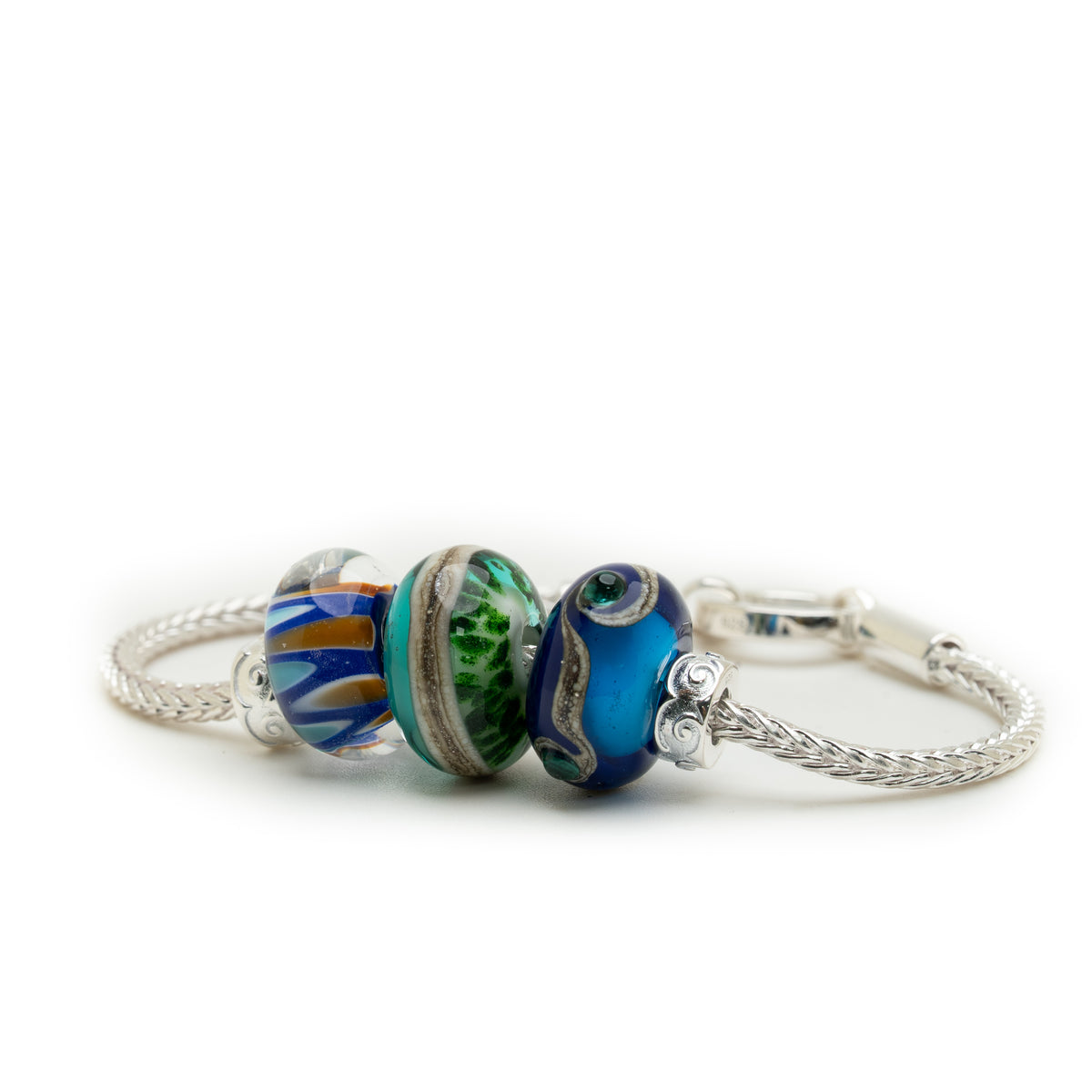 A silver-toned twist-wire charm bracelet with three decorative glass beads, including blue, green, and striped multicolor beads, shown on a white background.