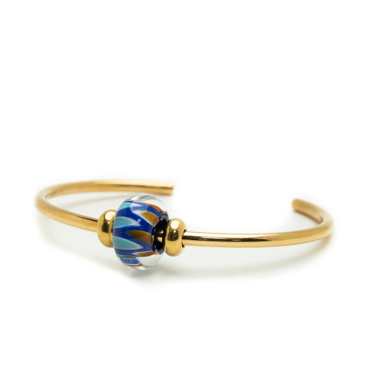 A gold metal cuff bracelet featuring a central glass lampwork bead with blue, white, and gold swirls, set against a plain white background.