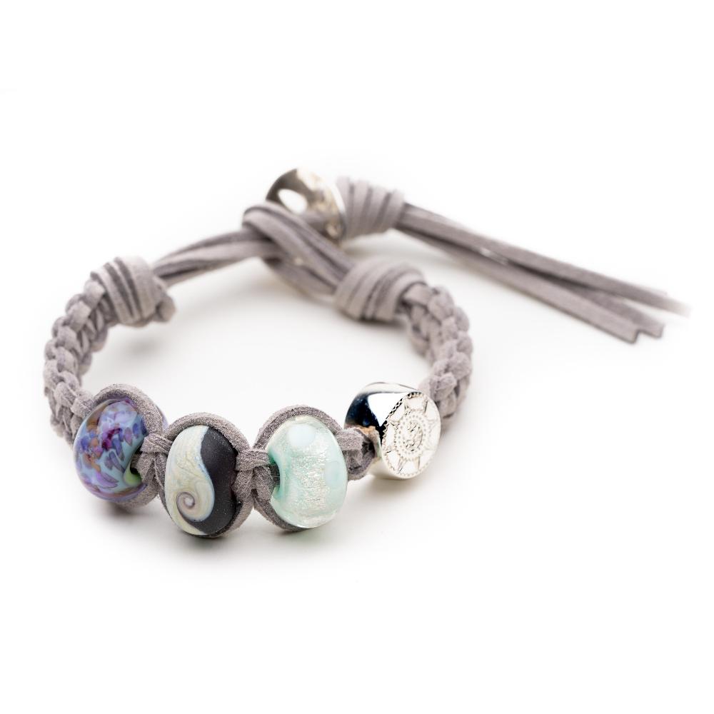 Grey macramé cord bracelet with purple, black and green glass beads and silver compass charm.