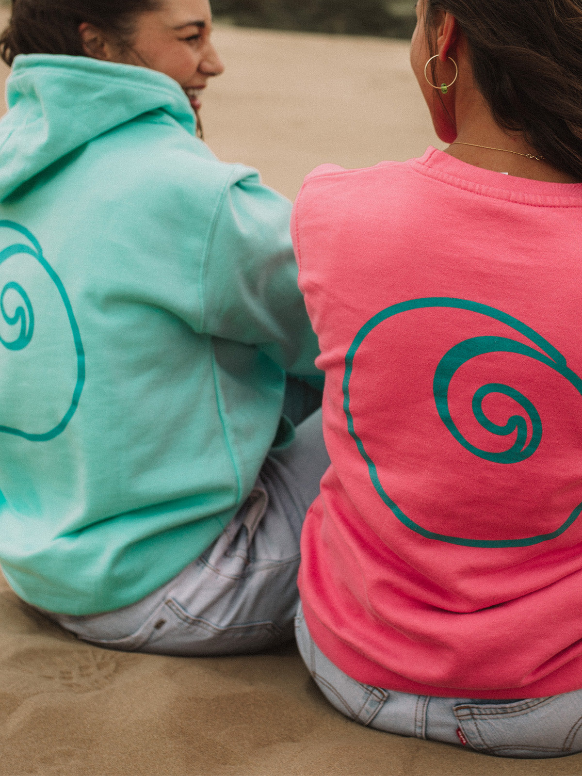 Unisex Pink and Mint Nalu Sweatshirts worn by girls on beach.