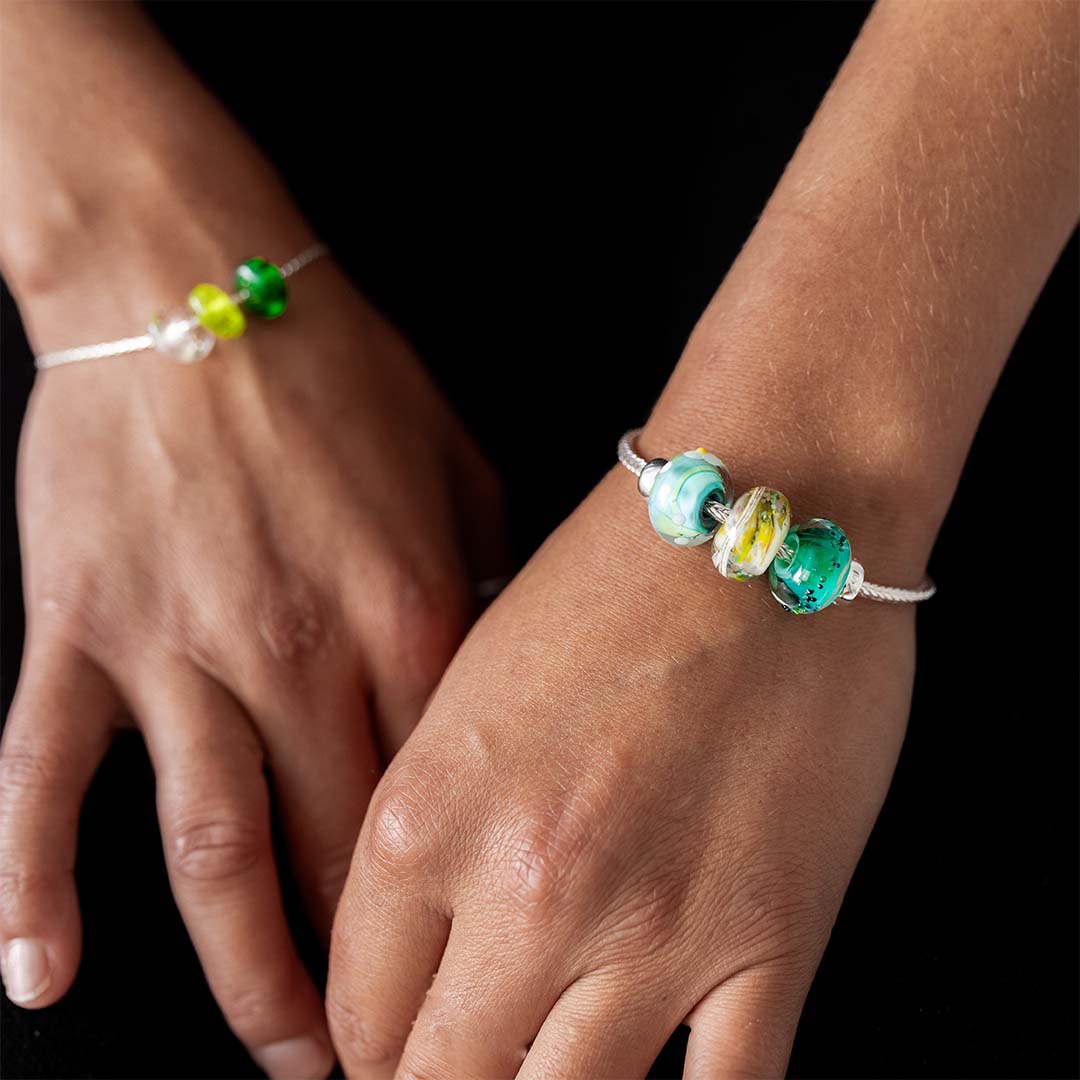 Woman wearing a black vest wearing a sterling silver bracelet with blue, green patterned glass beads