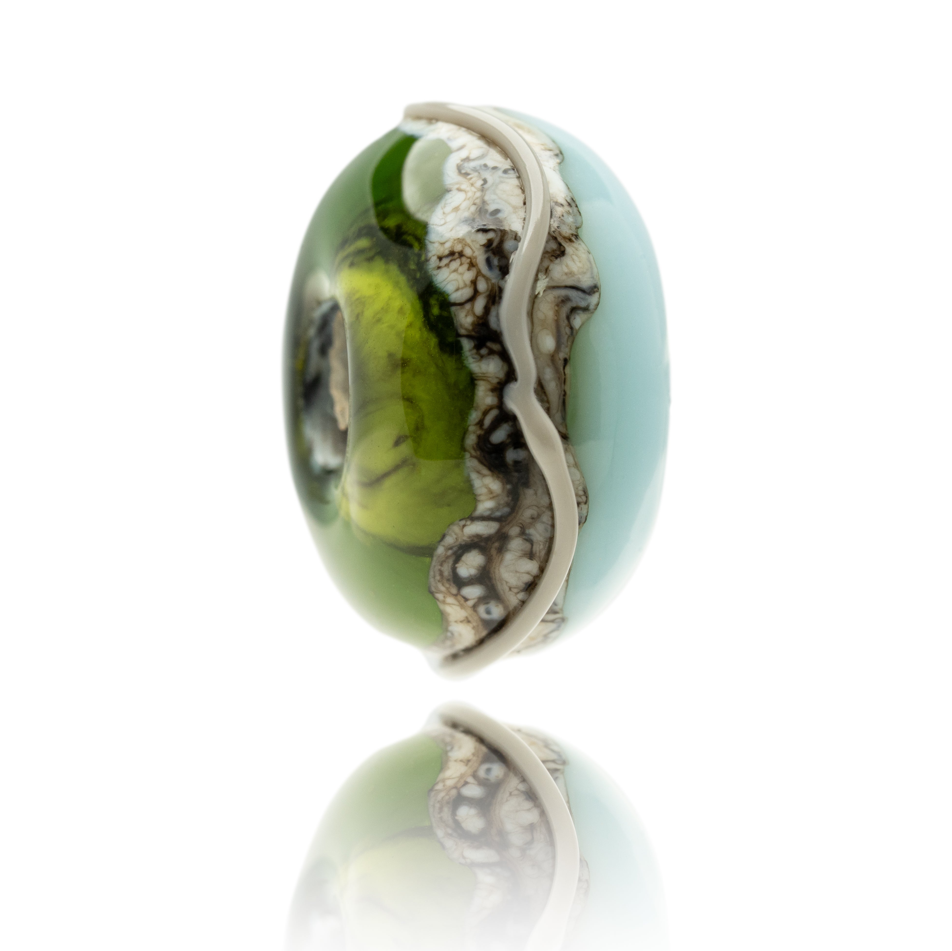 Blue, green and grey swirled glass bead on white background.