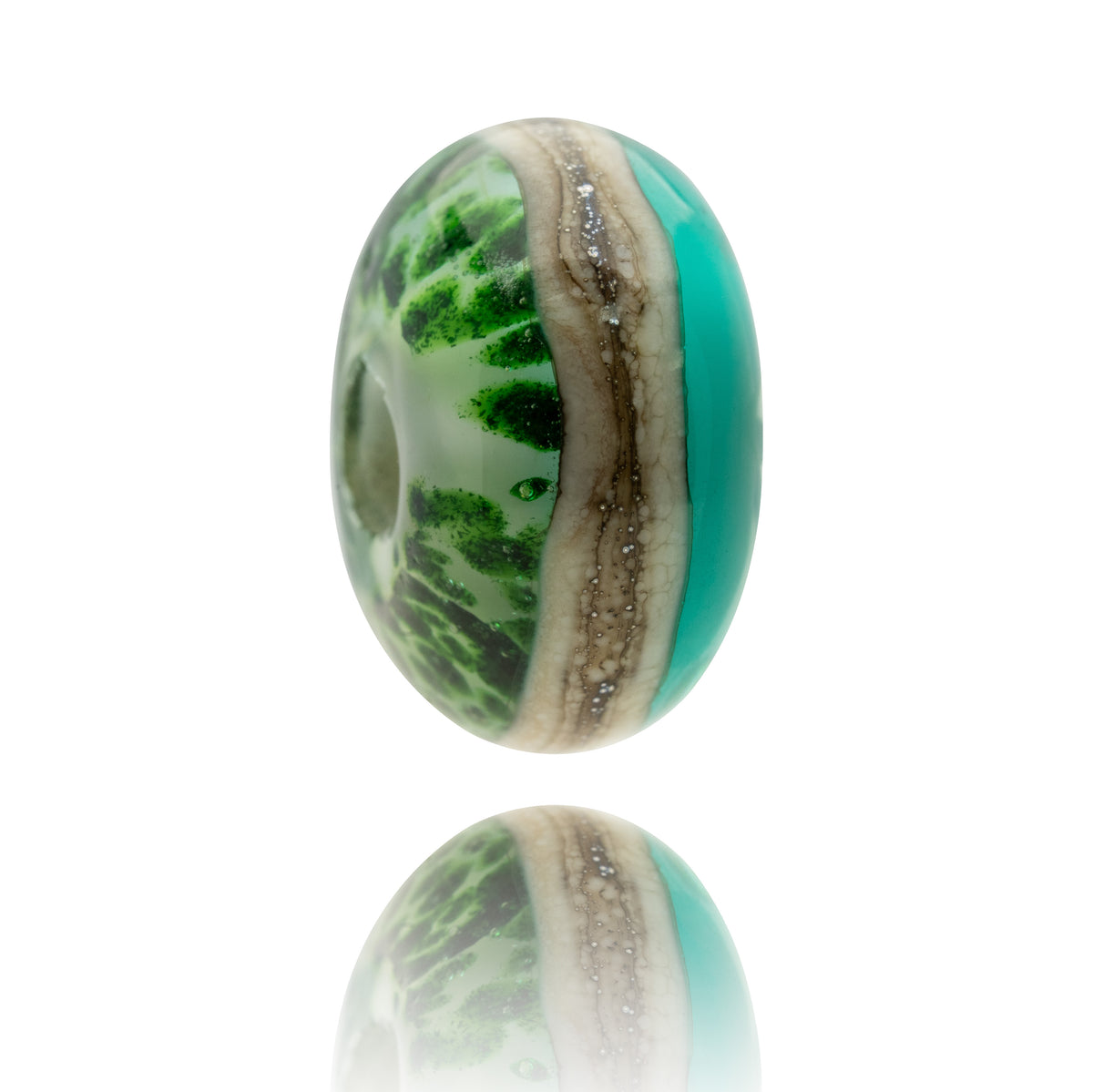 An oval glass bead with a marbled pattern of green, white, and turquoise, featuring a textured beige band with small silver glitter accents, shown on a white background with a soft reflection below.