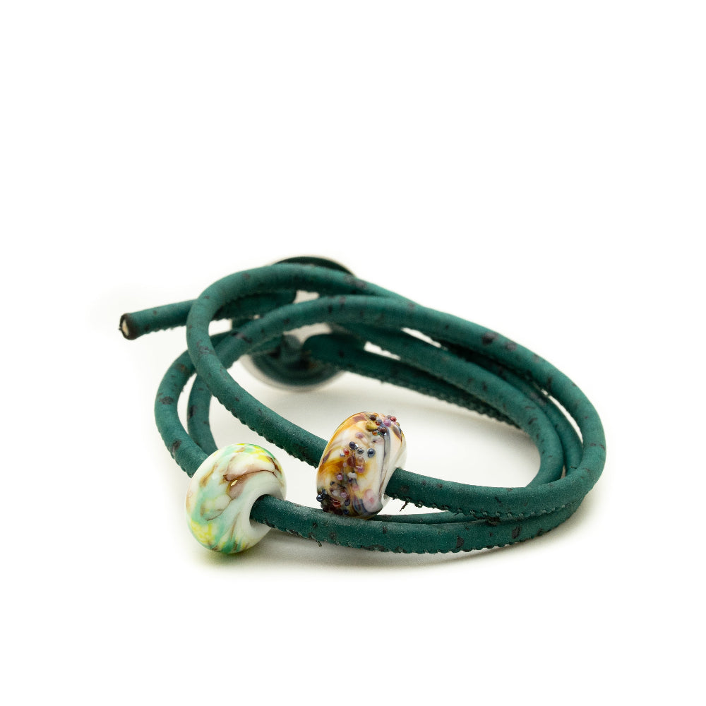 Green leather bracelet with two beads on a white background