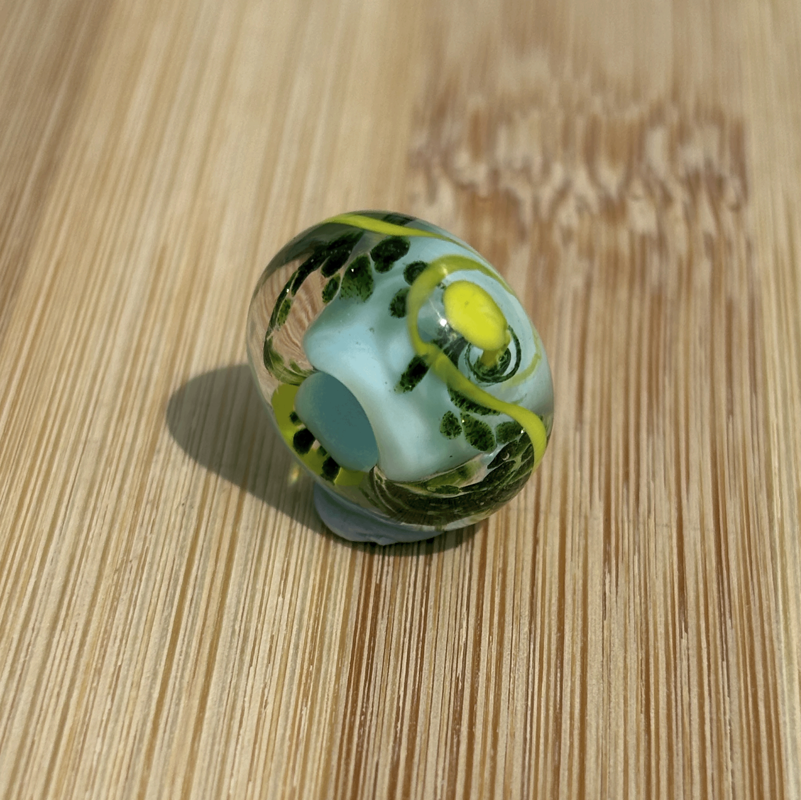 Blue, green and yellow glass bead being sold in support of EAND charity.