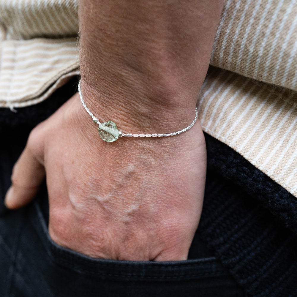 Close-up of a wrist wearing a silver bracelet with a green stone.
