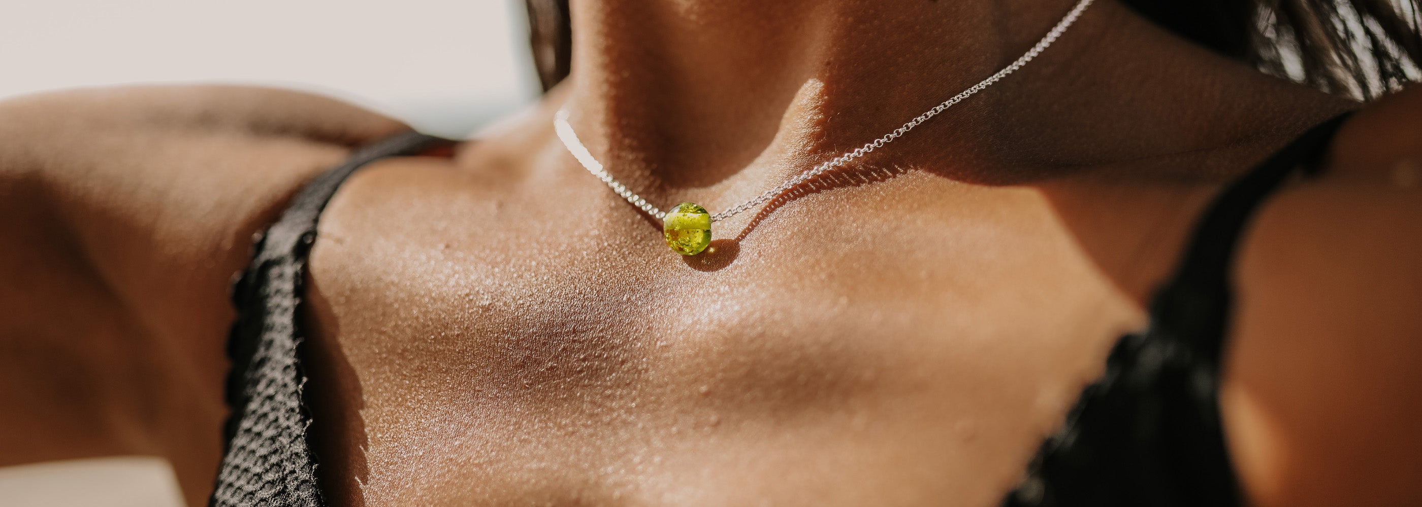 Bright green glass sand pebble on a silver necklace.