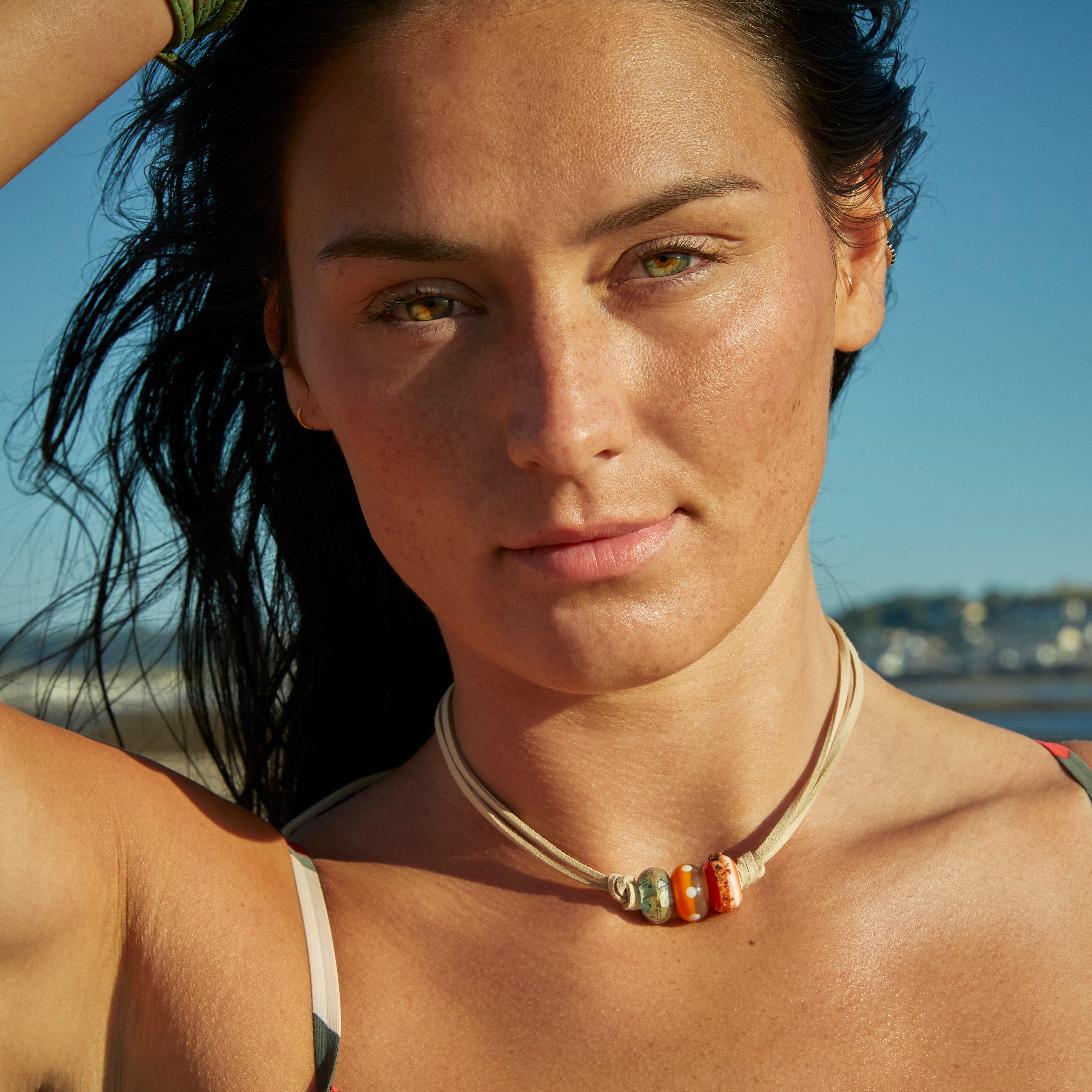 Girl on beach wearing simple cord necklace with three glass surf beach beads by Nalu.